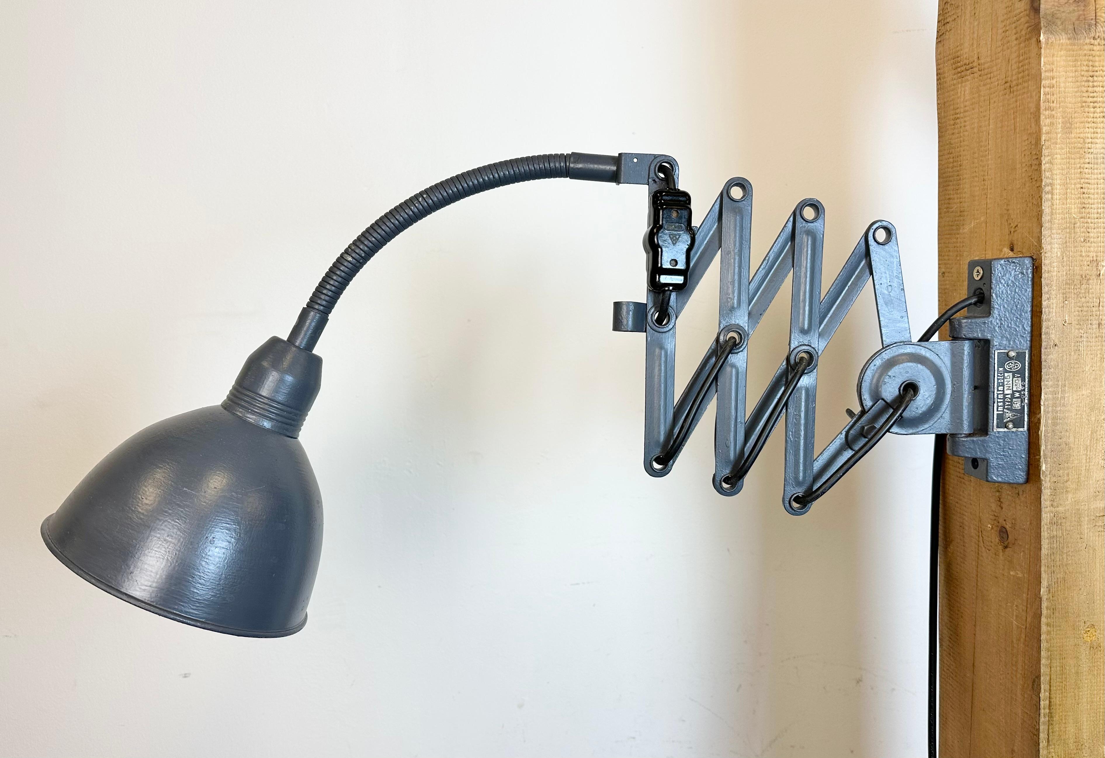 This vintage Industrial grey scissor wall light was produced by Elektroinstala Decín in former Czechoslovakia during the 1960s. It has a metal lampshade. The iron scissor arm is extendable and can be turned sideways. The socket requires E 27/ E26