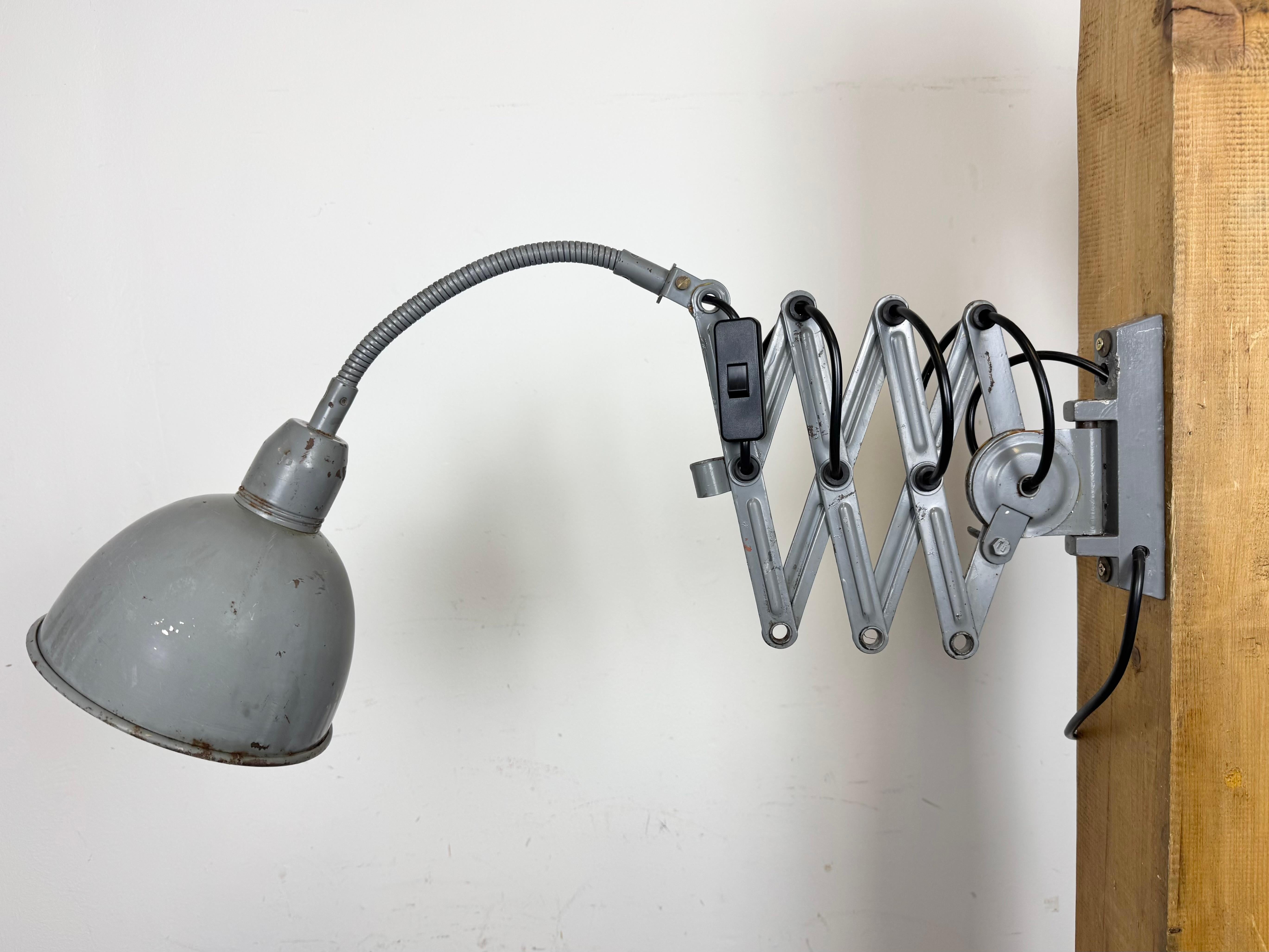 This vintage industrial adjustable gooseneck grey scissor wall light was produced by Elektroinstala Dečín in former Czechoslovakia during the 1960s. It has a metal lampshade. The iron scissor arm is extendable and can be turned sideways. The socket