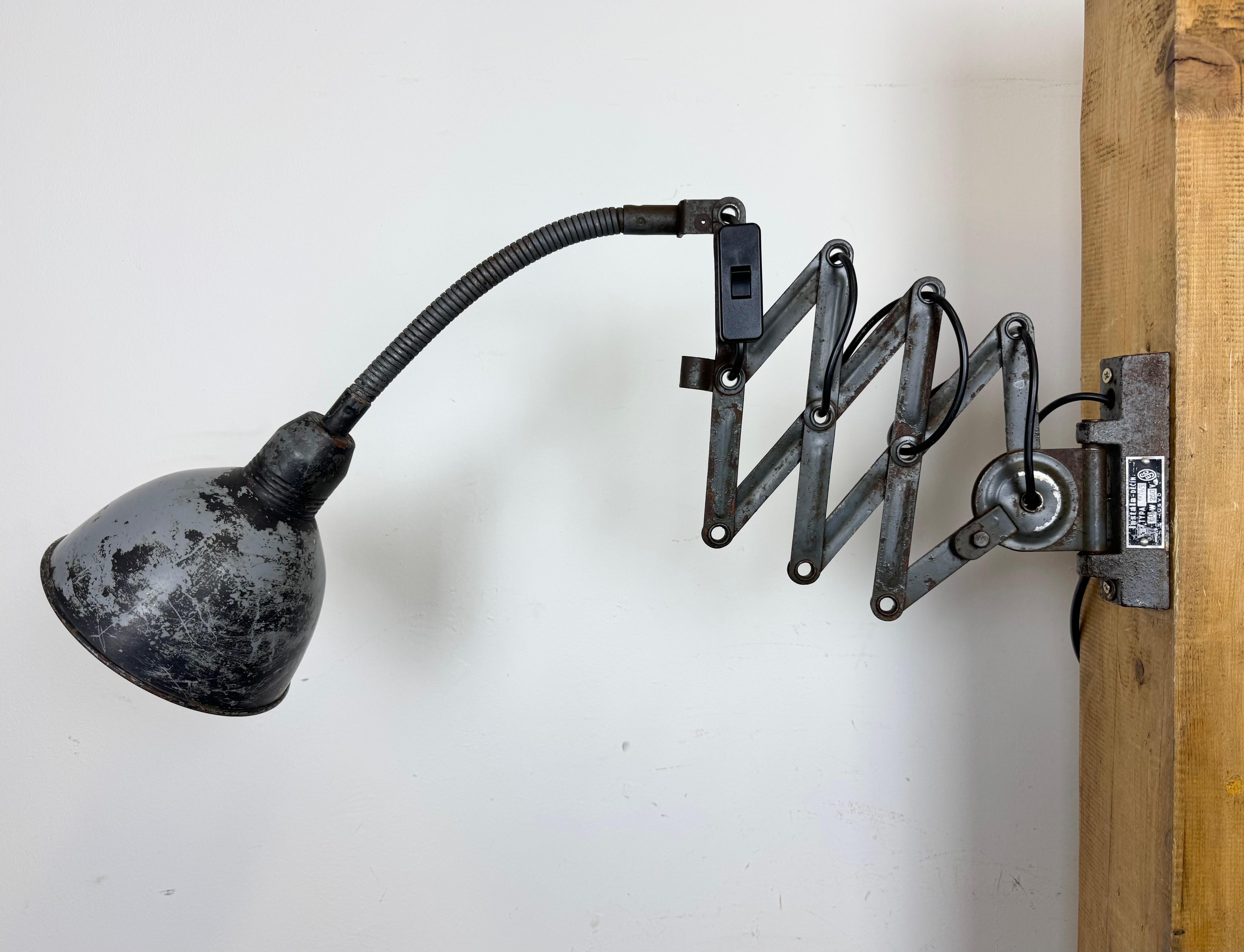 This vintage industrial adjustable gooseneck grey scissor wall light was produced by Elektroinstala Dečín in former Czechoslovakia during the 1960s. It has a metal lampshade. The iron scissor arm is extendable and can be turned sideways. The socket
