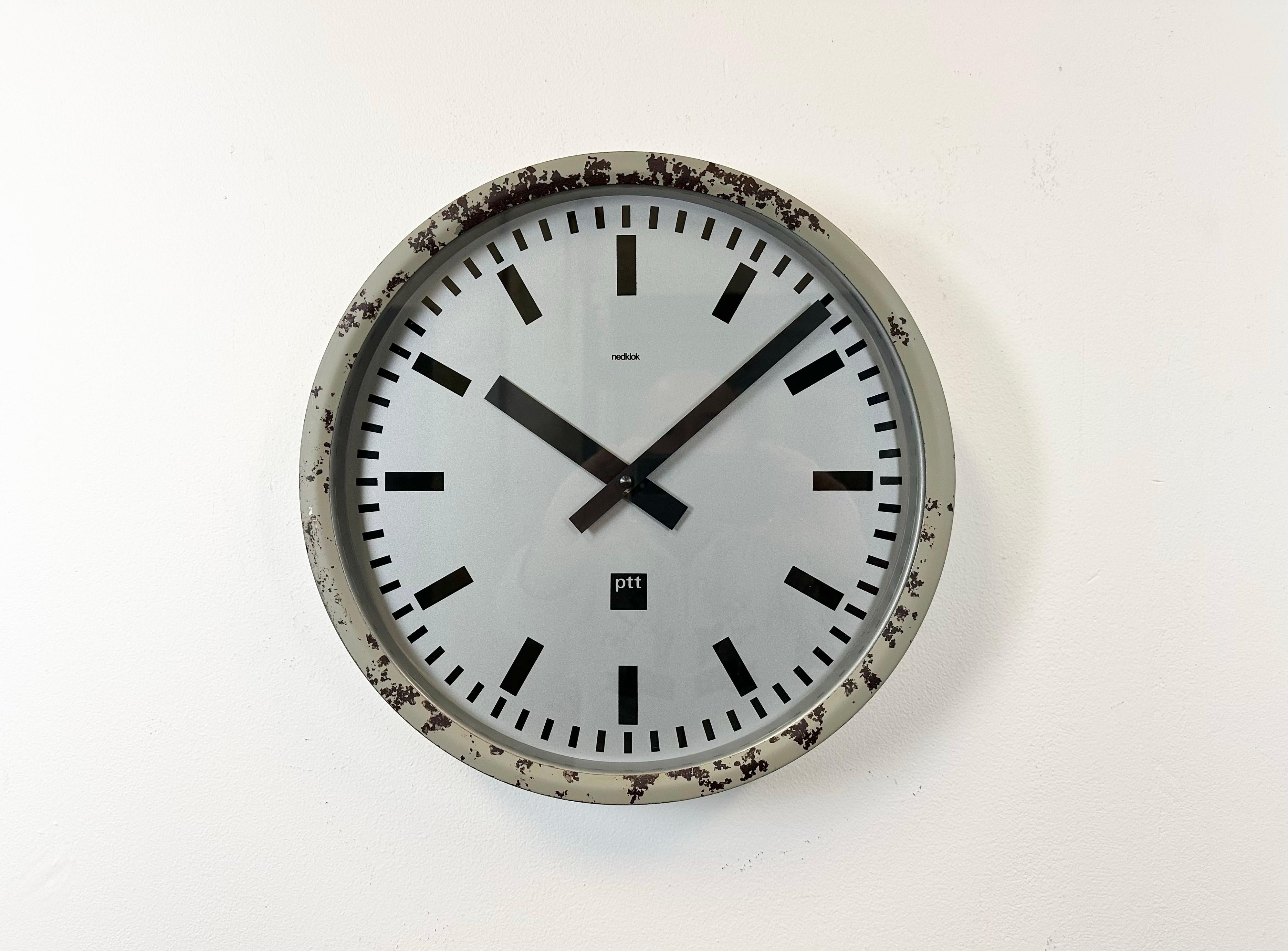 Nedklok wall clock was made in Netherlands during the 1960s. It features a grey iron frame, a metal dial, an aluminium hands and clear glass cover. The piece has been converted into a battery-powered clockwork and requires only one C- LR14 battery.