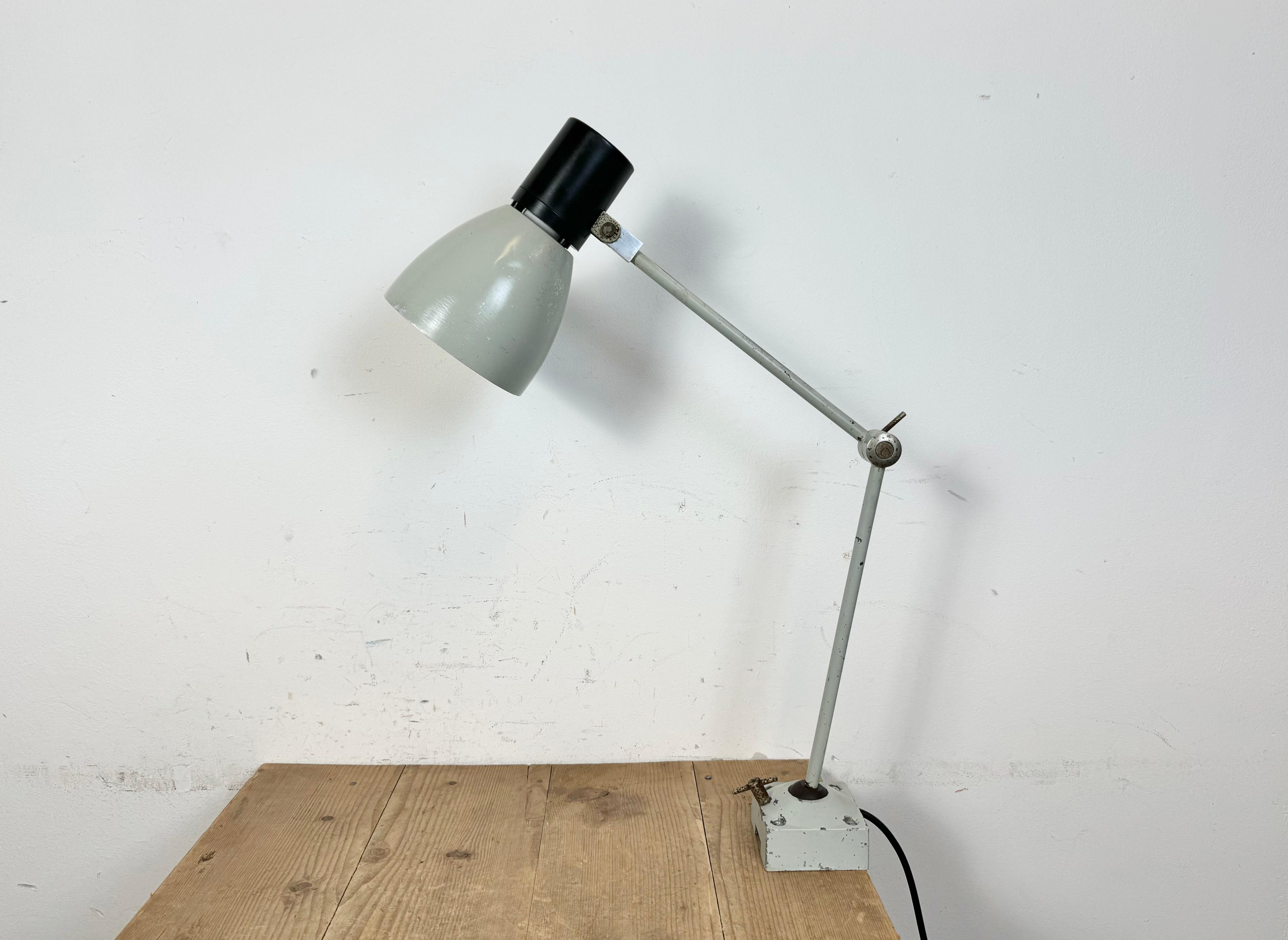 Industrial table lamp made by Elektrosvit in former Czechoslovakia during the 1970s. It features a grey iron base and arm with three adjustable joints and an aluminium shade with bakelite top. The original switch is situated on the top. The socket