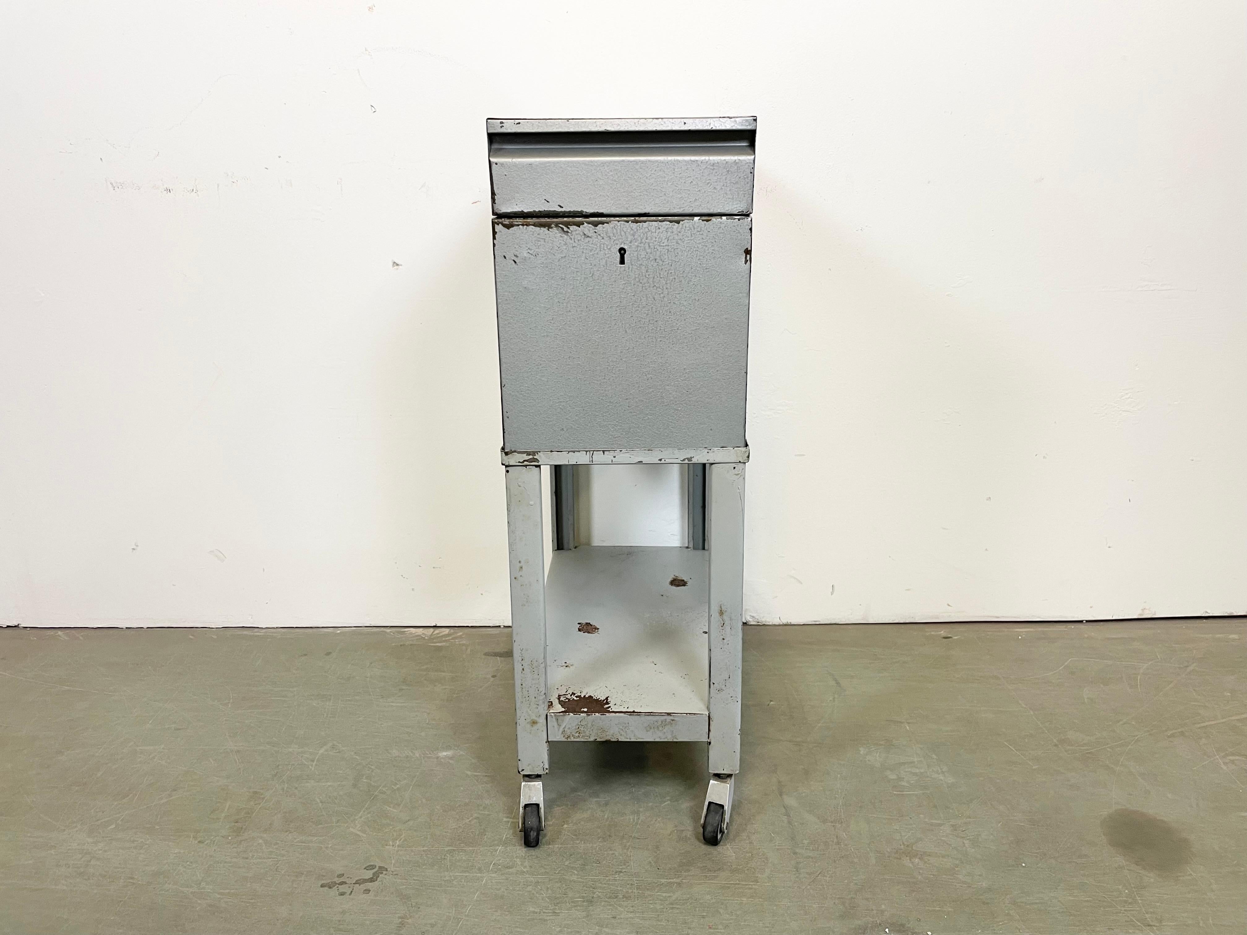 Vintage industrial box on wheels, ( former filling cabinet ) ,was made by Obzor Košice in Slovakian part of former Czechoslovakia during the 1960s Now can be serves as a cart bar or nightstand. It features a grey hammerpaint metal box and grey iron