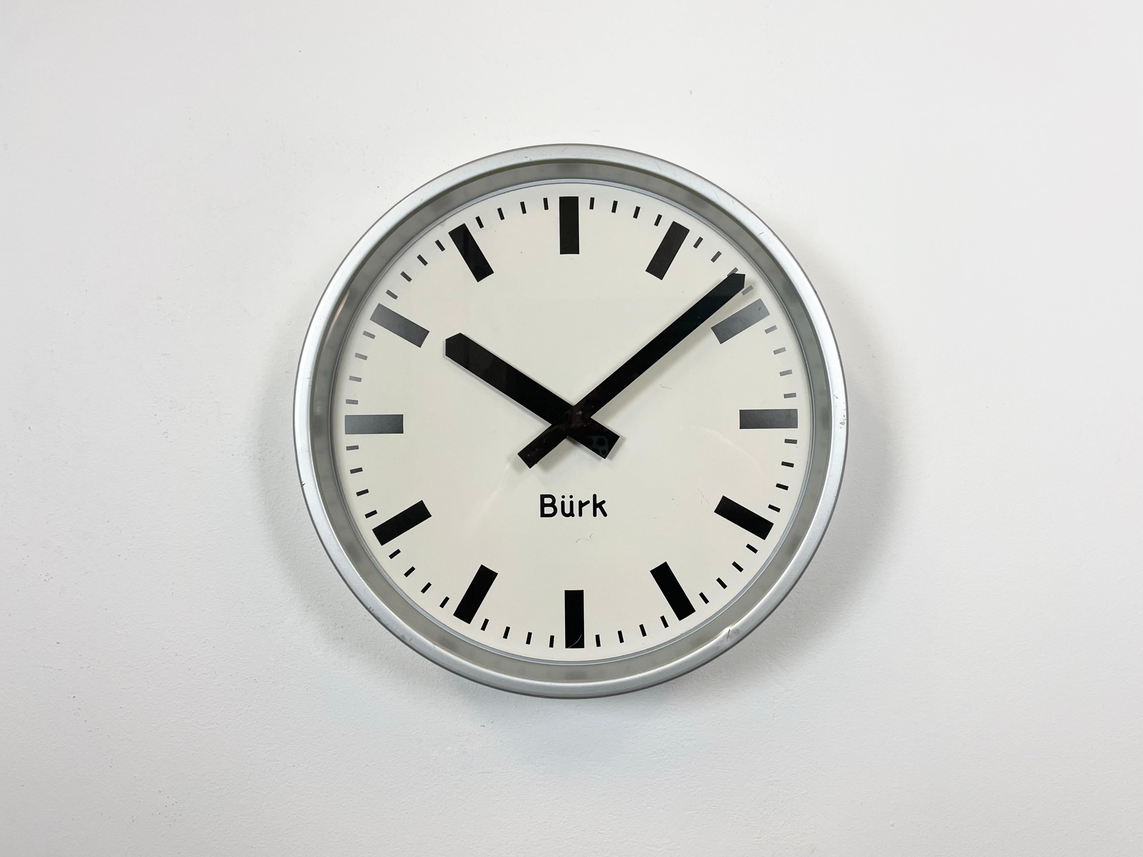 Burk wall clock was made in Germany during the 1960s. It features a grey iron frame, a metal dial, an aluminium hands and clear glass cover. The piece has been converted into a battery-powered clockwork and requires only one AA-battery. The diameter