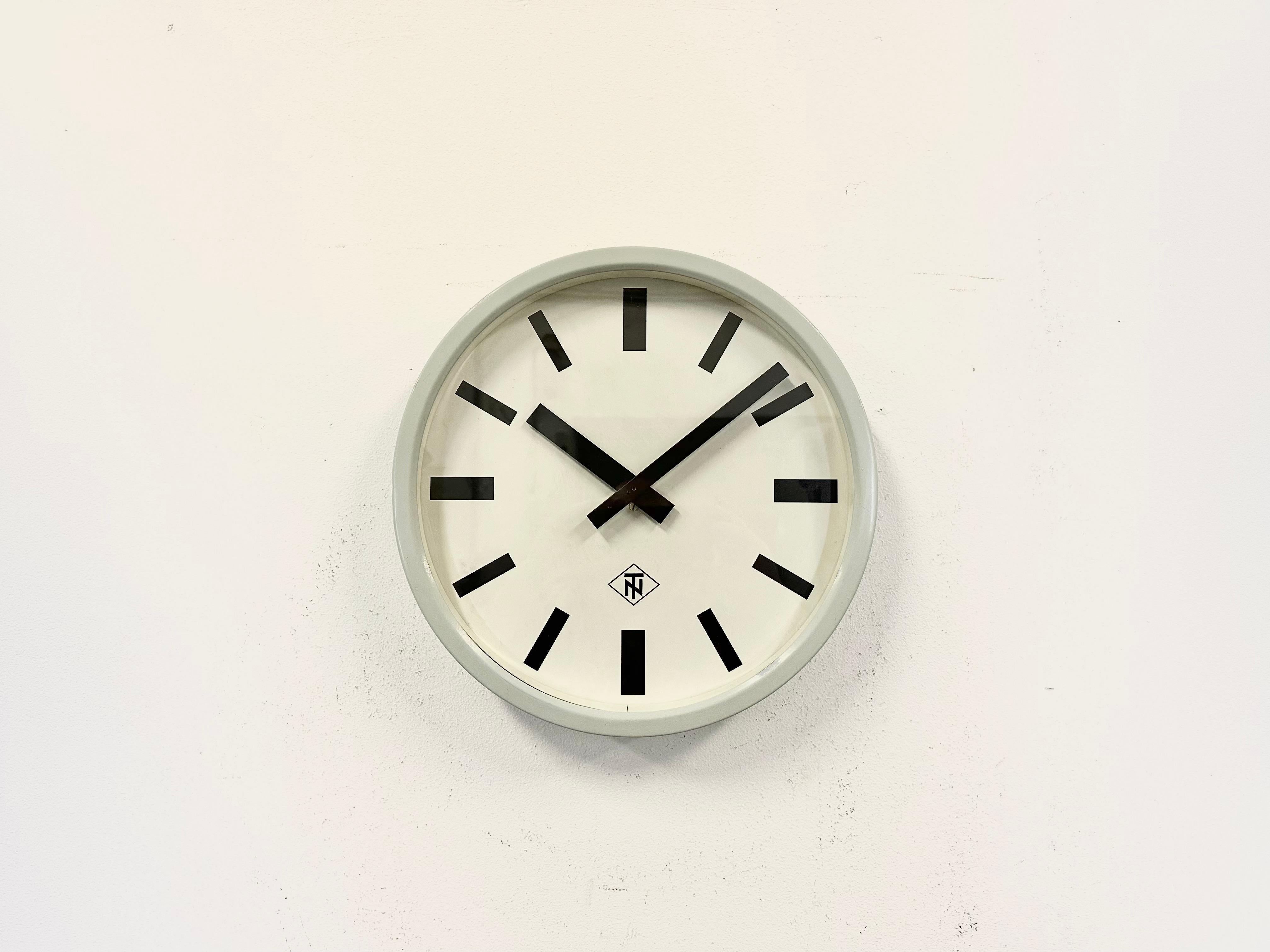 Wall clock produced by TN Telefonbau und Normalzeit in Germany during the 1960s. It features a grey iron frame, a white metal dial, an aluminium hands and a clear glass cover. The piece has been converted into a battery-powered clockwork and
