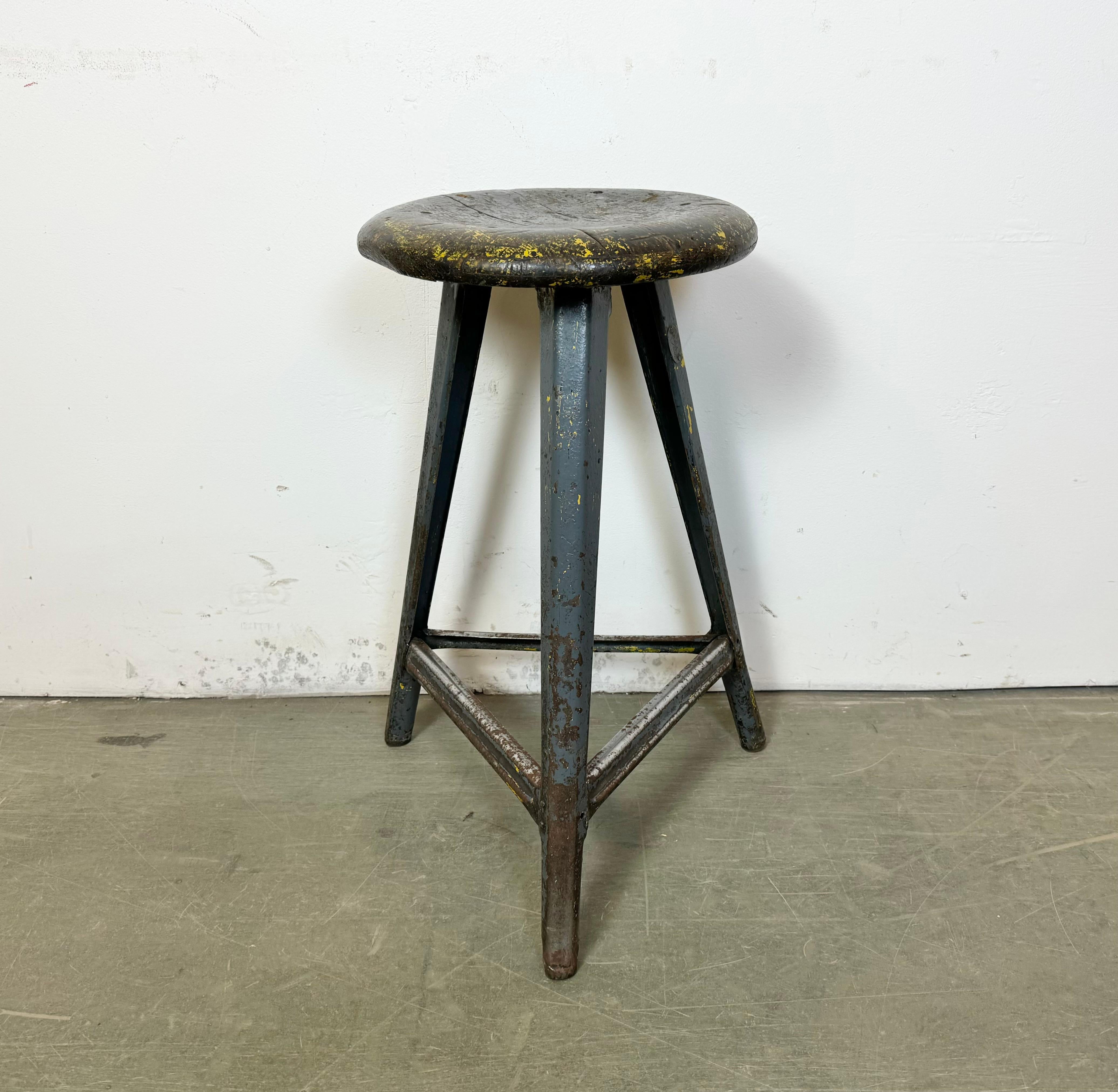 Vintage-Industriehocker, hergestellt in der ehemaligen Tschechoslowakei in den 1960er Jahren. Sitz aus Holz und graues Metallgestell. Das Gewicht des Hockers beträgt 6 kg.