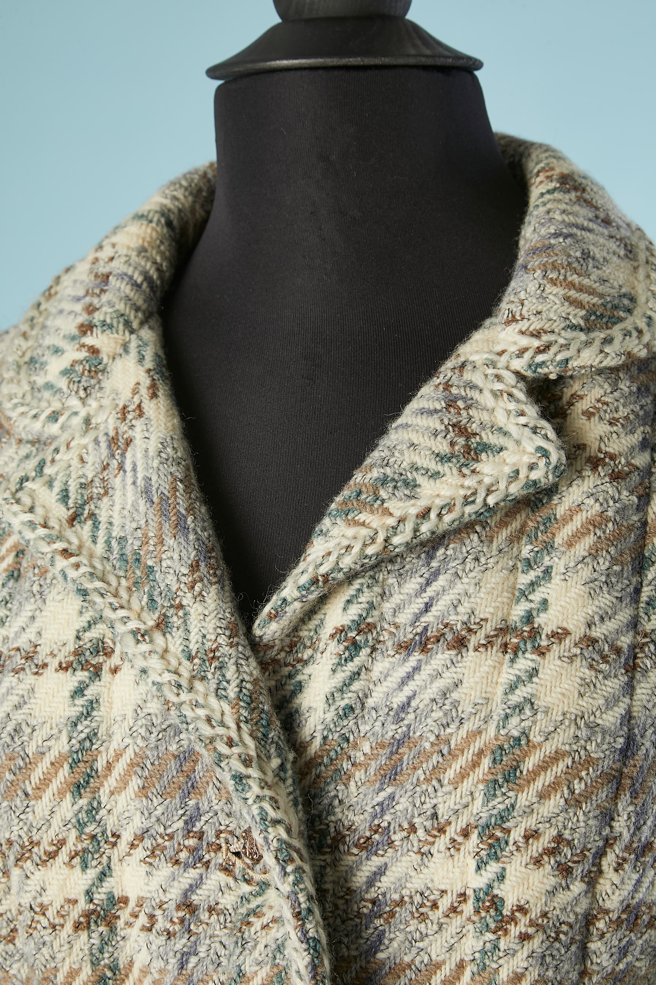 Combinaison jupe en tweed gris, ivoire et bleu. Composition du tissu : laine. Doublure en soie (d'origine à l'intérieur de la veste et plus récente à l'intérieur de la jupe) Bouton en métal et tweed. Demi-courroie. Surpiqûres verticales pour