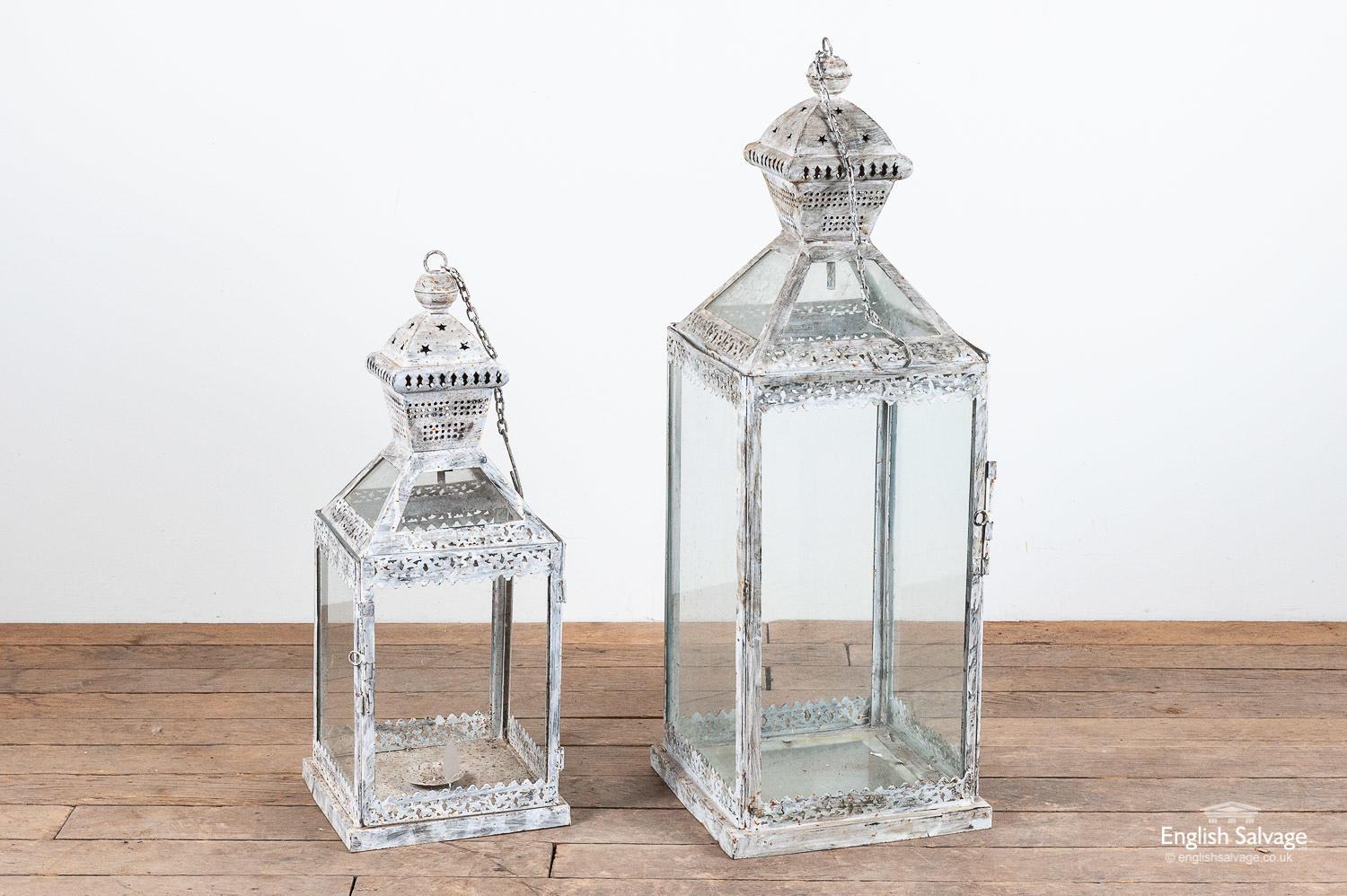 Attractive candle / tealight lanterns with a distressed grey paint finish and pretty latticework and stars detailing. Hanging chains and hinged doors. The smaller one is missing two panes of glass to the sides. Measurements below are for the larger