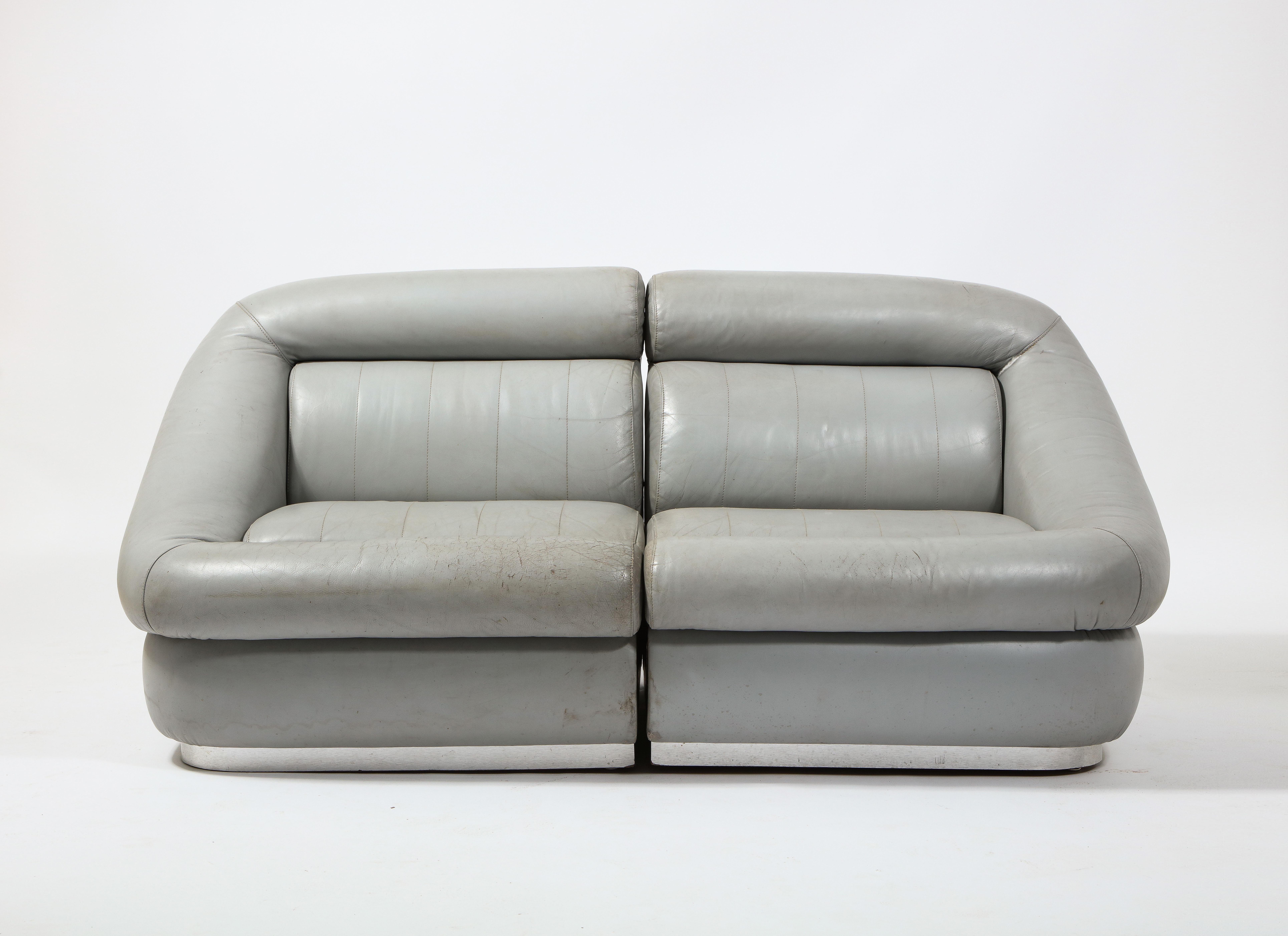 Elegant and comfortable two-piece settee in original gray leather on aluminum-clad bases. 

Two matching settees are available. They are priced individually.
