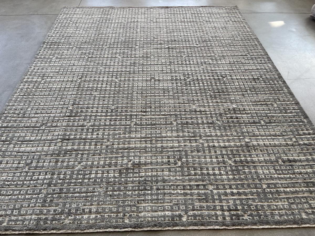 Low pile cut fibers alternate with woven negative spaces to create a multi-layered effect in this contemporary design. Neutral grey tones make for a very forgiving rug while wool construction adds extra durability. Hand made in India using vegetal