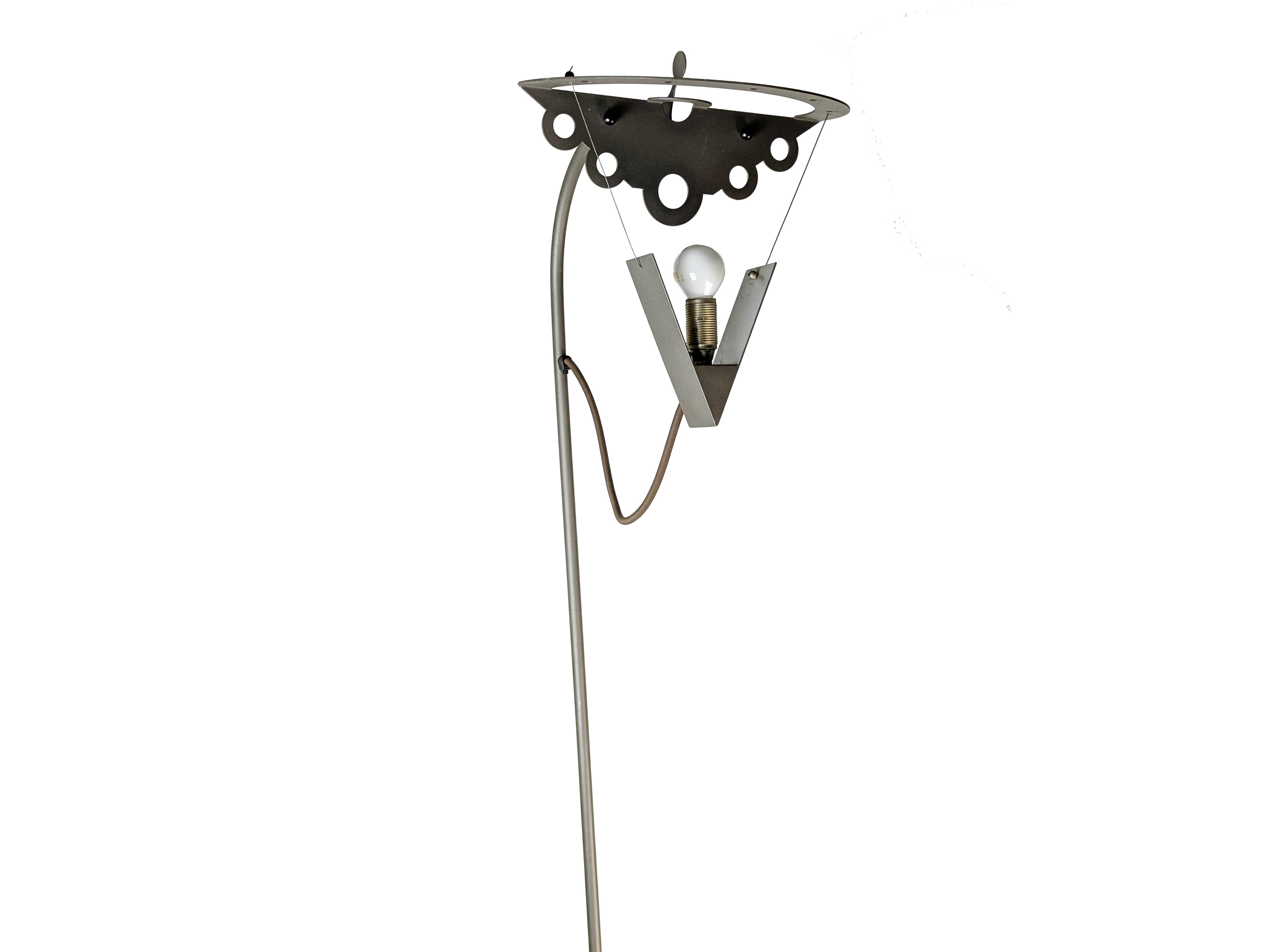 Curieux lampadaire en métal peint gris foncé, plié, soudé et perforé. Probablement produit entre la fin des années 80 et le début des années 90. Porte-lampe avec support triangulaire suspendu à deux câbles en acier. Câble électrique recouvert d'une