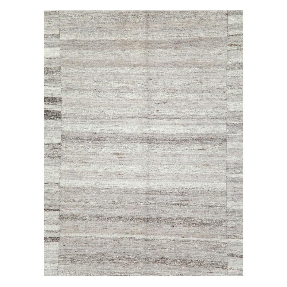 A vintage Turkish flat-weave Kilim accent rug handmade during the mid-20th century made up of 3 columns with several horizontal variating shades of color in grey (gray), white, and charcoal. The overall effect is a grey toned minimalistic piece that