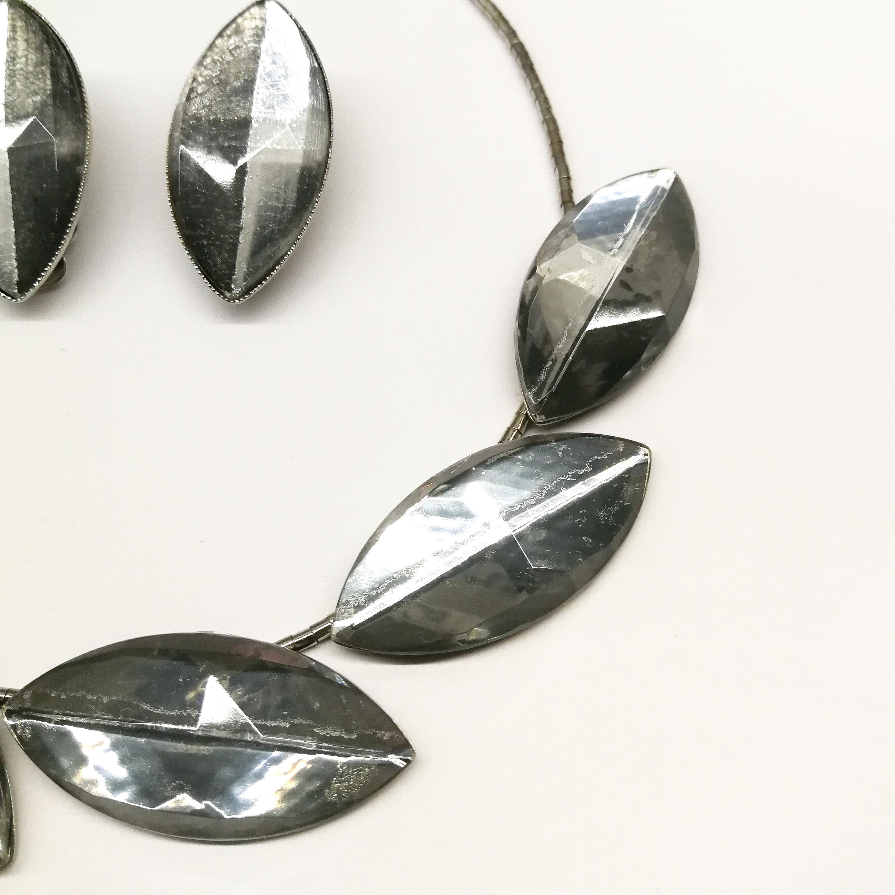 An unusual and striking necklace and earrings from this German designer, always innovative and distinctive. Constructed with very small individual metal 'beads' that form the line of the necklace, large oval and faceted smokey grey/silvery flat back