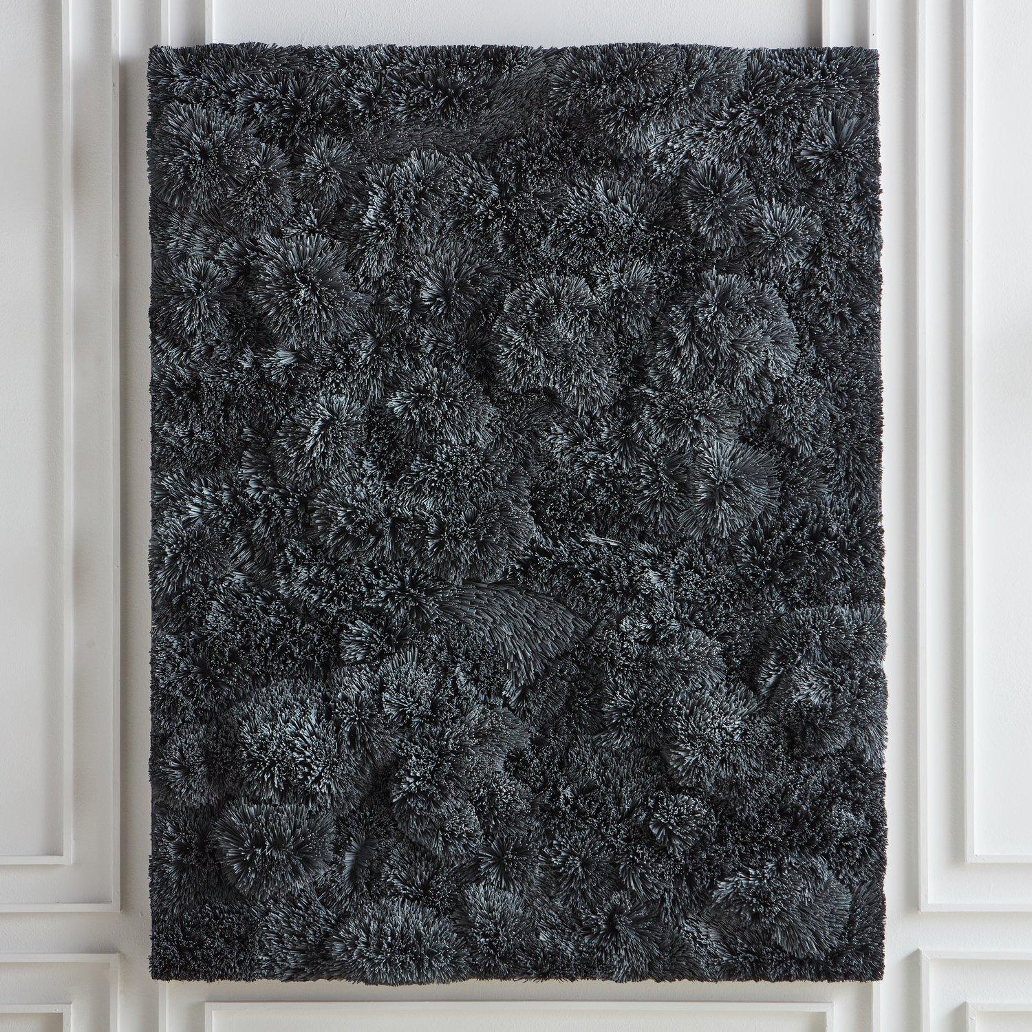 A mixed media wall sculpture by Canadian artist Erin Vincent, 2022. Composed of organic bristles, foam, and acrylic. A monochromatic dark grey piece with subtle nuances in tones. Her work is inspired by the beauty and simplicity of nature and