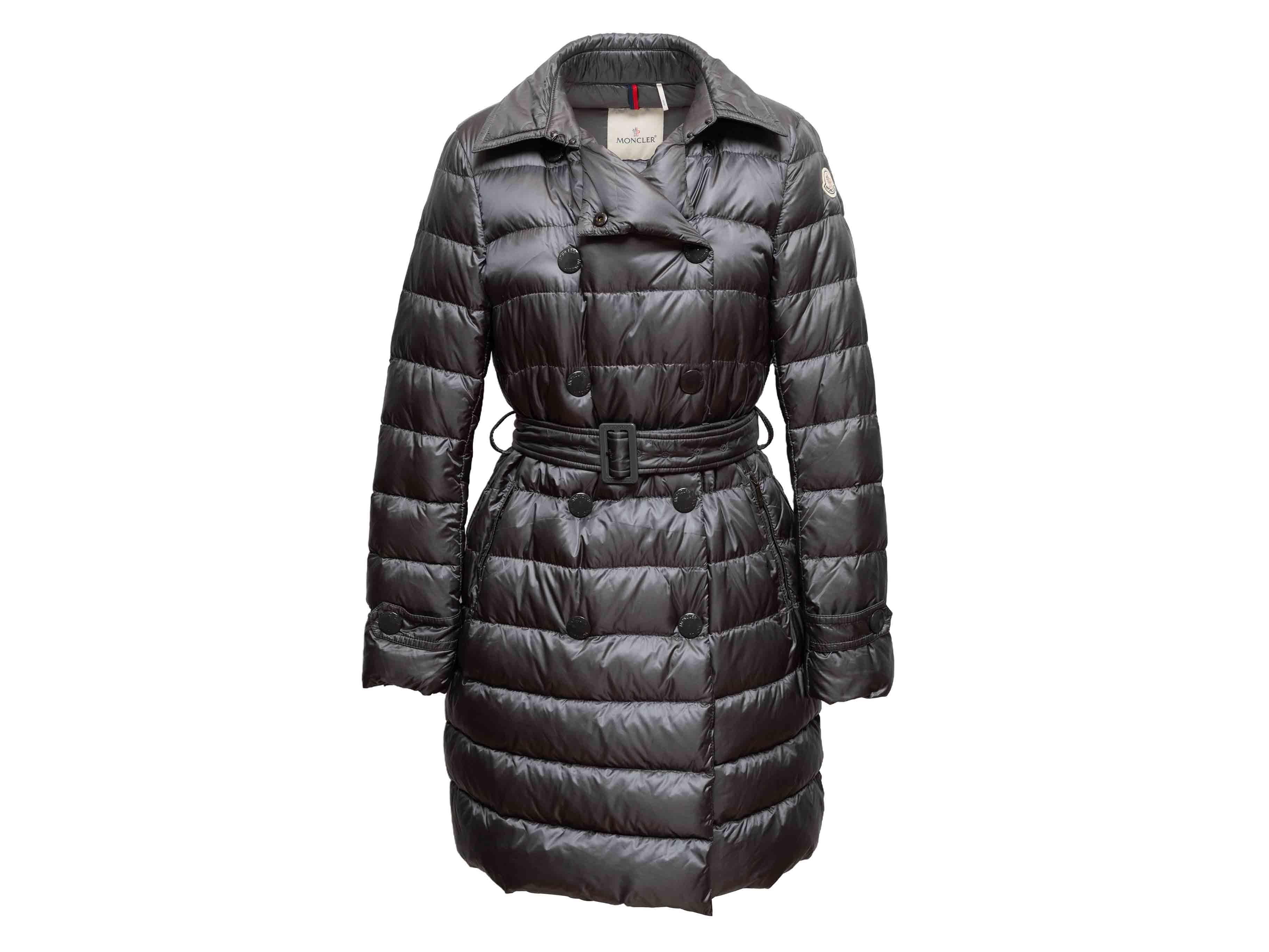 Cappotto in piuma d'oca doppiopetto grigio di Moncler. Collo a punta. Doppie tasche sui fianchi. Cintura in vita. Chiusura frontale con zip e bottoni automatici. Seno 41