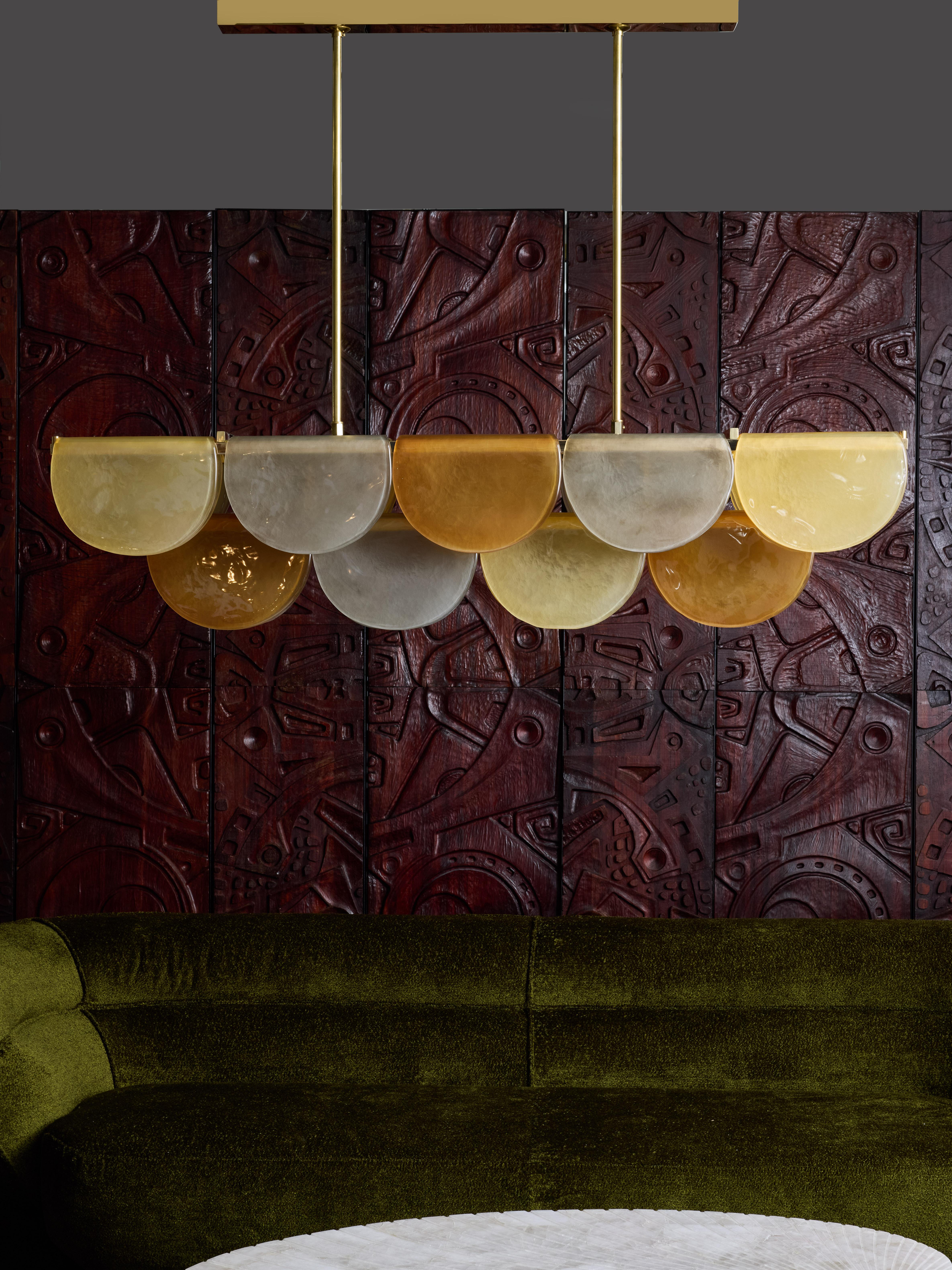 Long chandelier made of a brass structure with three levels, enlightened with LED strips running all the length.
Each level is covered with Murano glass plate as if it was folded around the structure.
