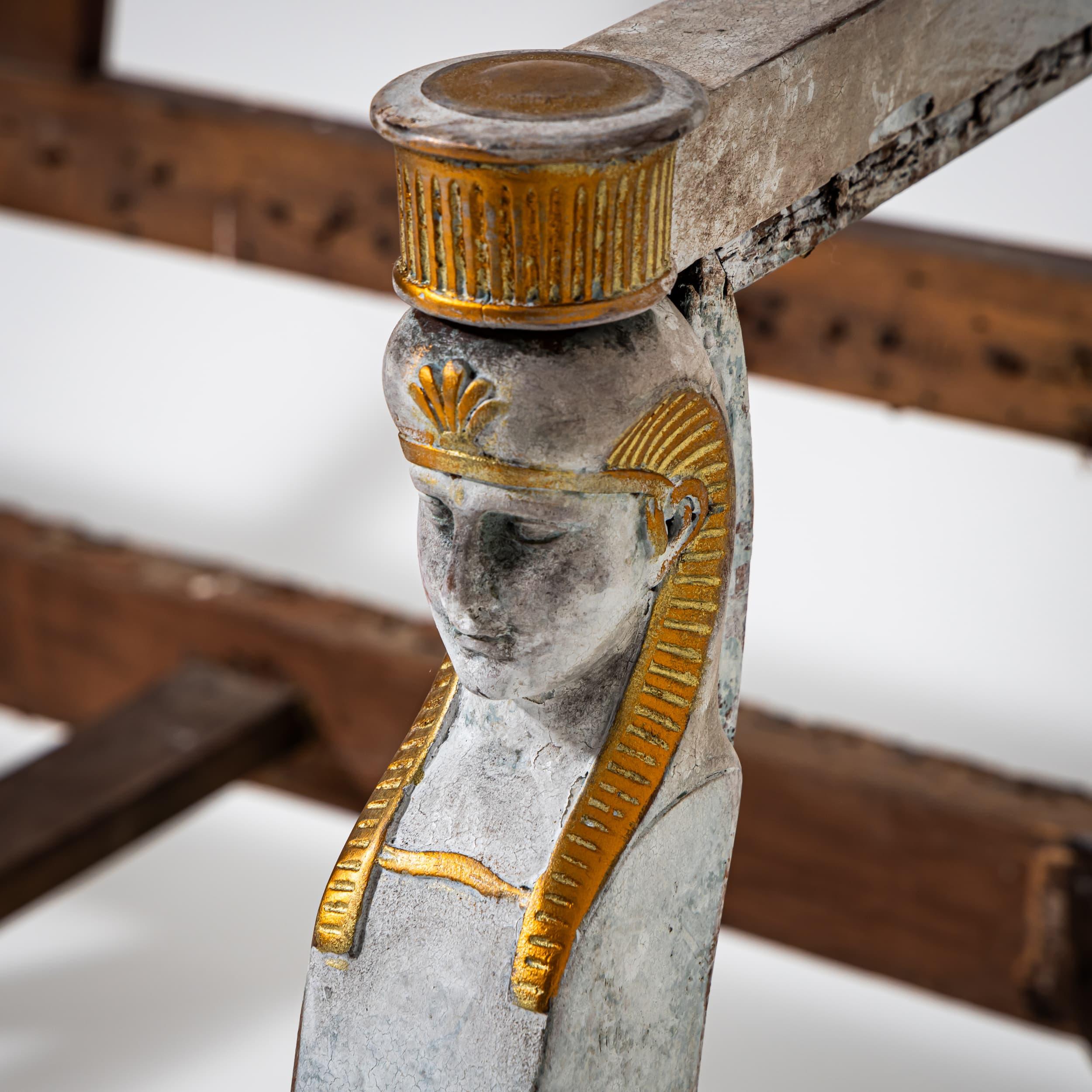 Canapé trois places de style Empire avec un dossier haut et droit et des accoudoirs droits terminés par des figures de cariatides de style égyptien. Le canapé repose sur sept pieds effilés et a été récemment peint dans un gris doux avec des reflets