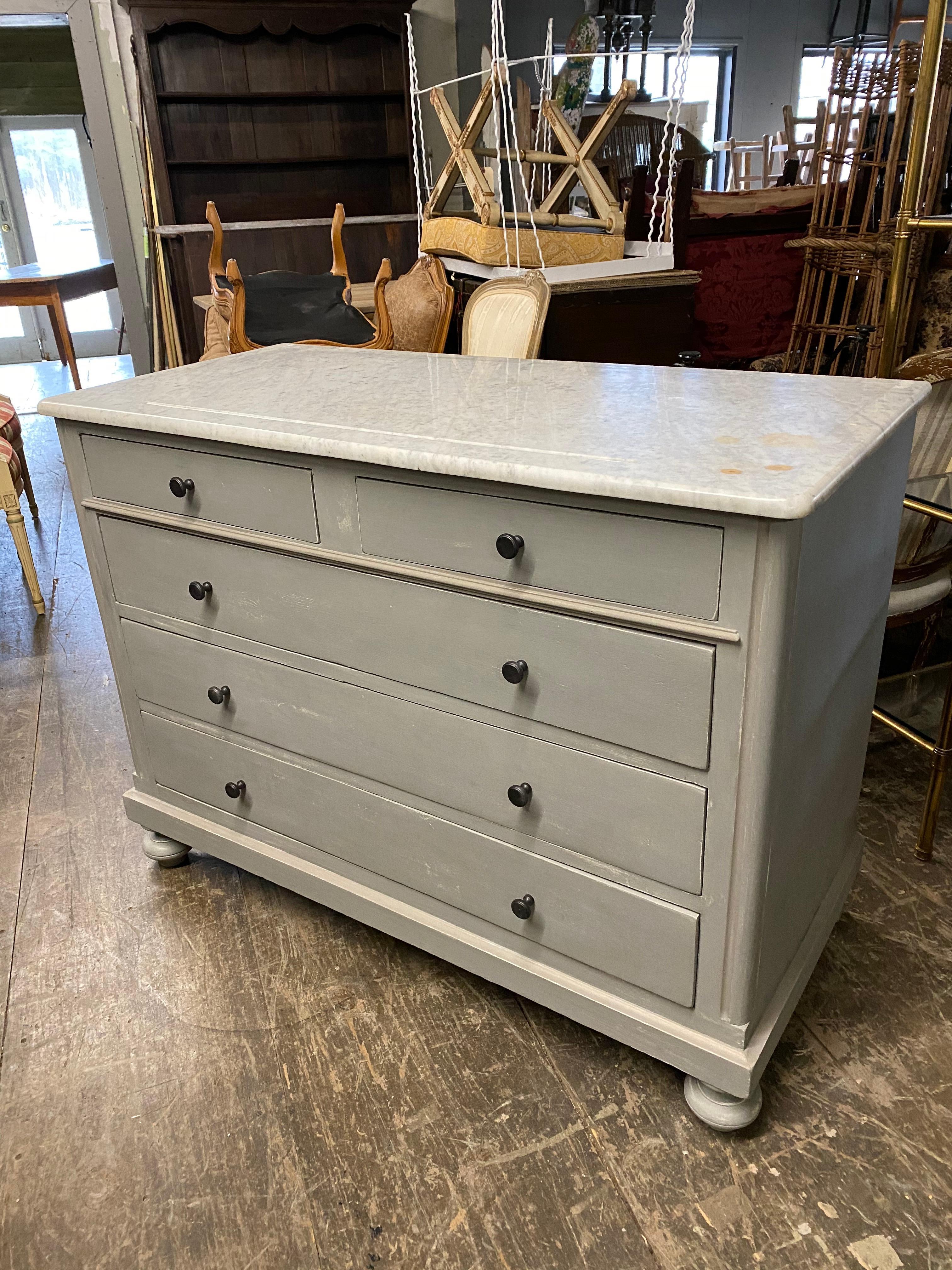 A classic American five-drawer custom painted chest with five drawers with marble top. The chest of drawers or dresser, painted in a Swedish Gustavian grey has two top drawers and 3 lower larger drawers. With iron pulls. The marble top shows aged
