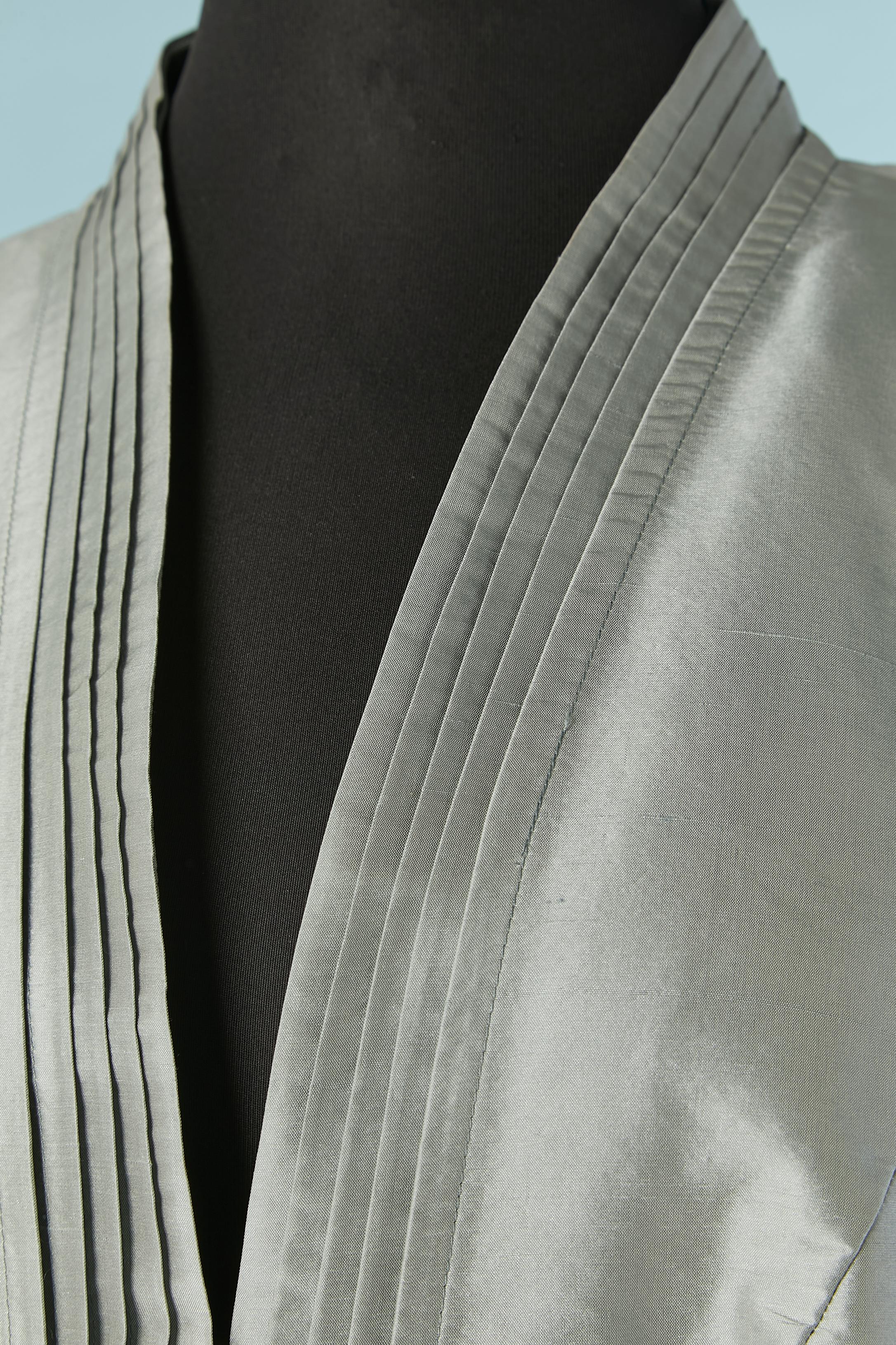 Grey raw-silk skirt suit with pleated neckline. Lining composition: 60% acetate, 40% cotton. There is lining inside the shoulder and inside the sleeves and otherwise it's piping. Buttons in the middle front with flower pattern and one extra button