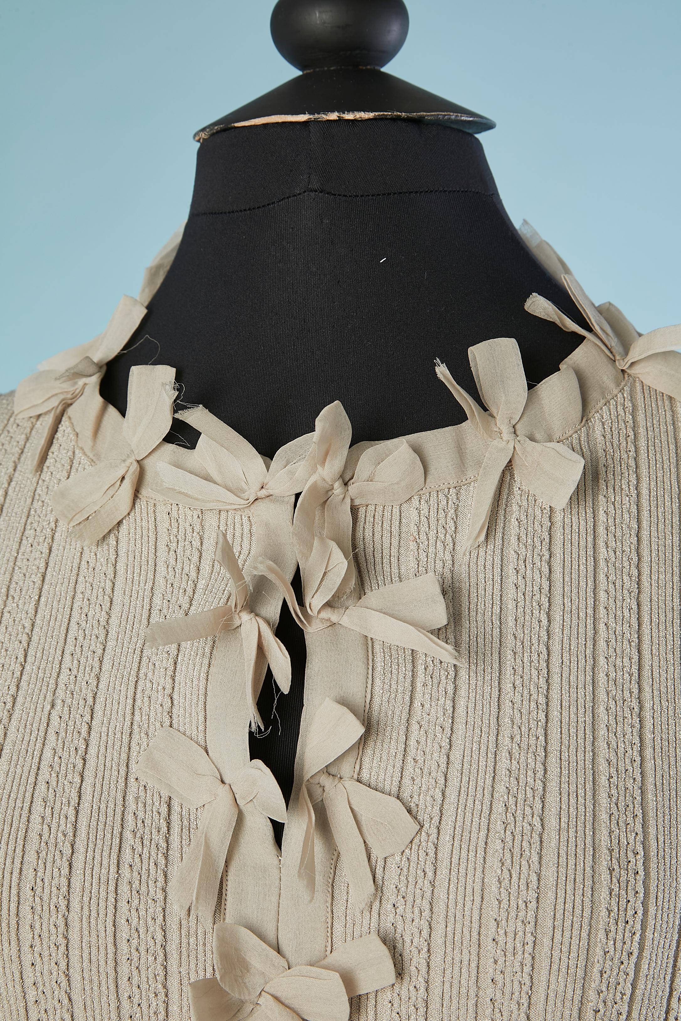 Pull en rayonne gris avec nœud en organza de soie au milieu du devant et poches. Petit CC en strass sur la poche gauche. 2 crochets au milieu du devant sur le dessus. Composition du tissu : 76% rayonne, 24% spandex (élasthanne) 
TAILLE 48 (I.L) 44