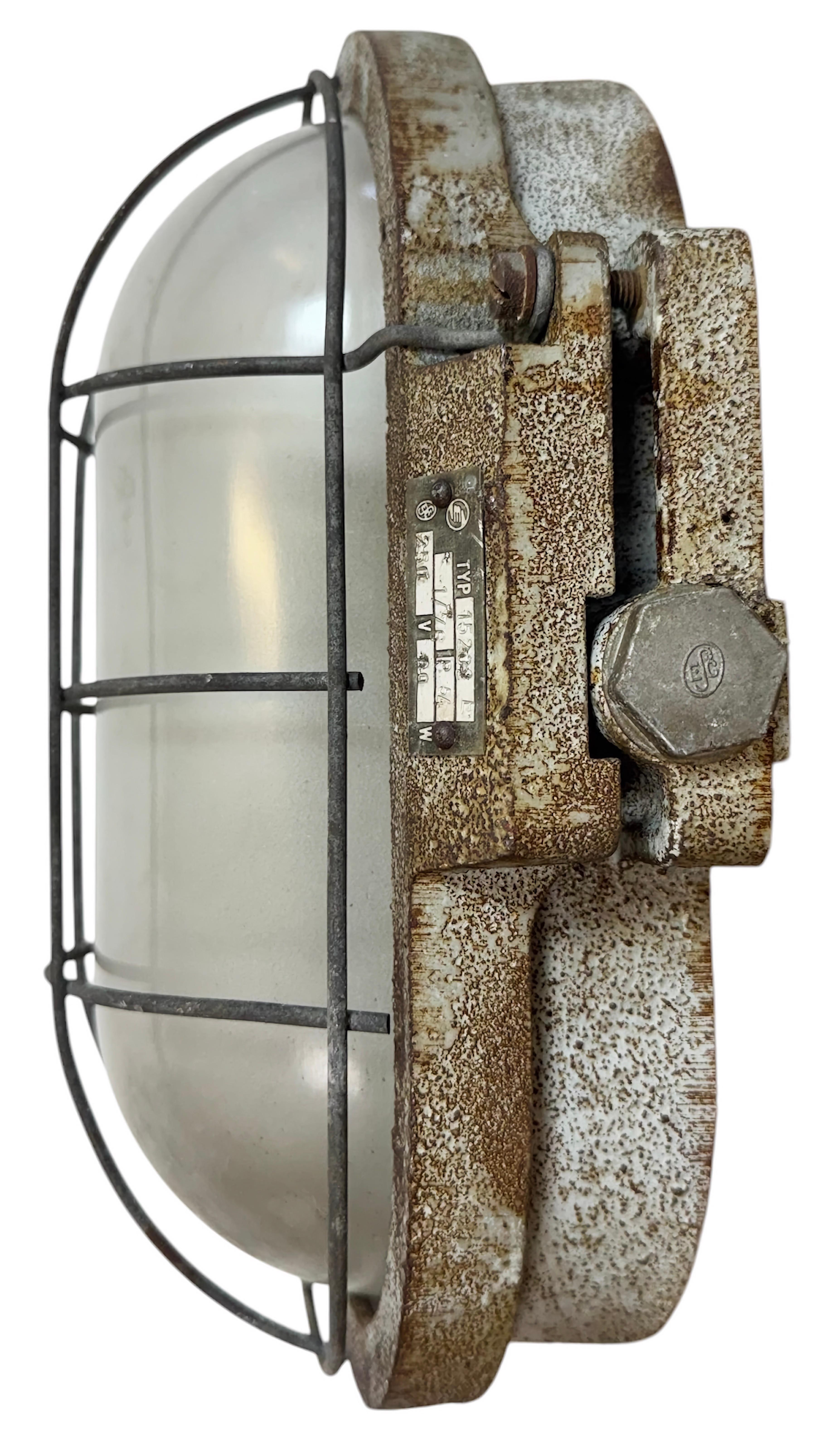 Applique industriale realizzata da Elektrosvit nell'ex Cecoslovacchia durante gli anni '1960. Il corpo è in ghisa, il coperchio in vetro lattiginoso e la griglia in acciaio. La presa in porcellana richiede lampadine E 27. Un nuovo cavo. Il peso