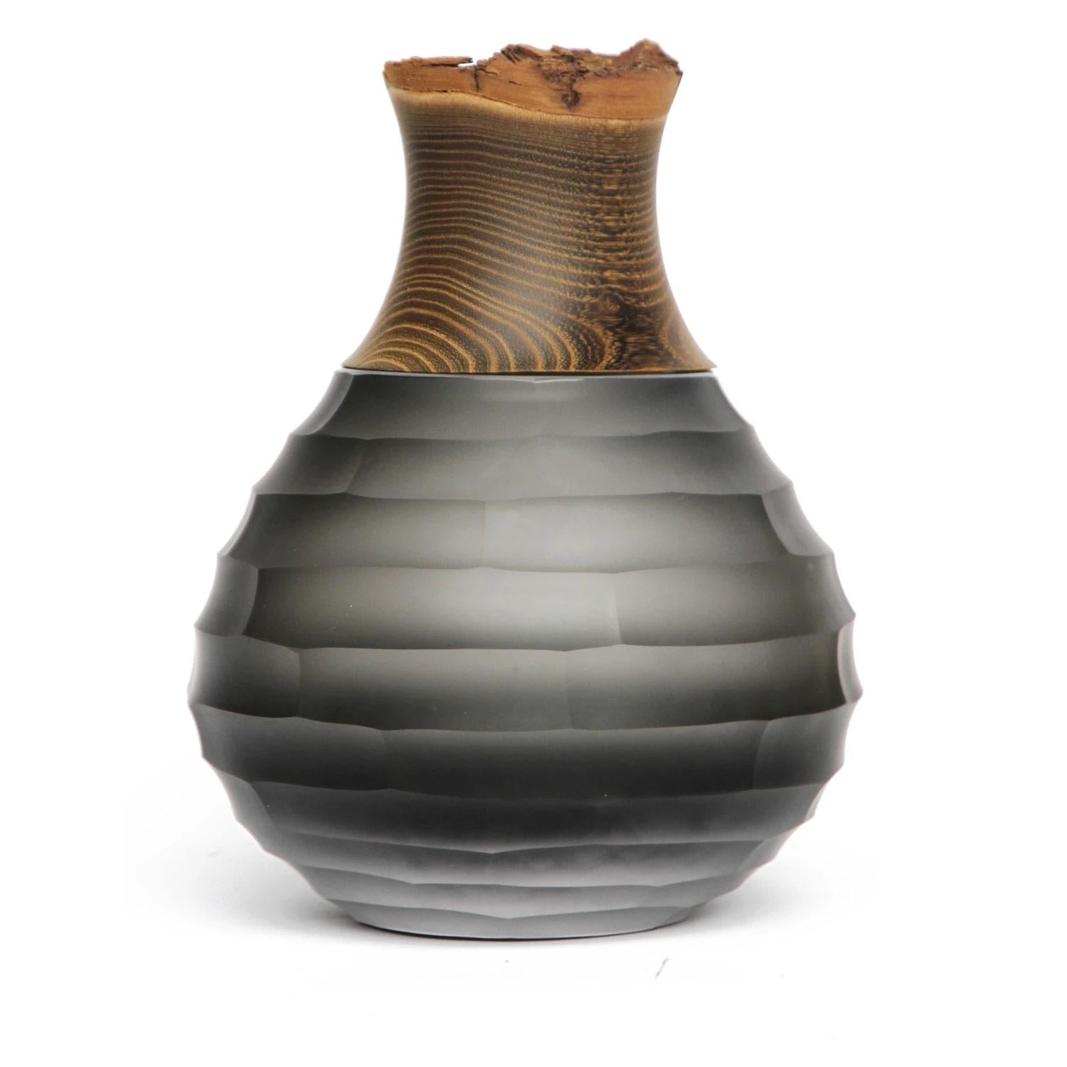 Grey sculpt stacking vessel, Pia Wüstenberg
Dimensions: D 23 x H 30.
Materials: cut glass, wood
Available in other colors.

A Stacking Vessel with large overlapping diamond wheel cuts ranging from rough to fine.
Handmade in Europe: hand blown and