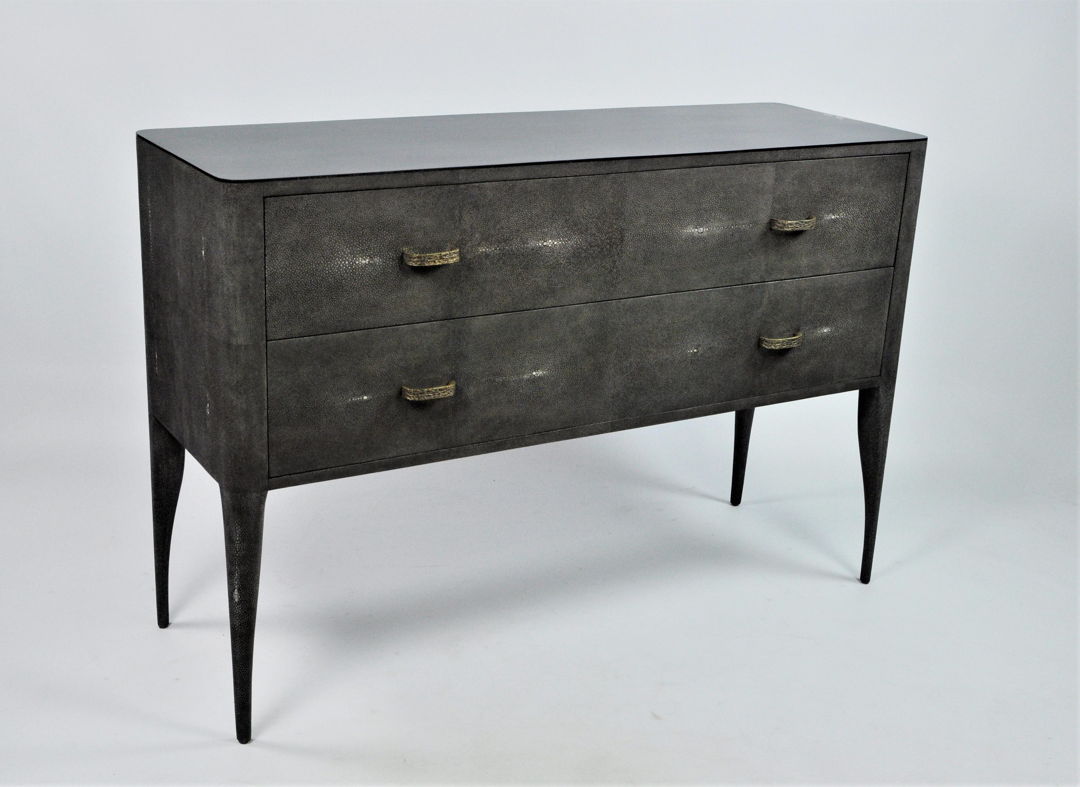 This beautiful organic chest of drawers is made of dark grey shagreen (our ref CARBON).
It has 2 drawers, and the top is inlaid with a polished black stone marquetry.
The drawers have lost wax cast brass handles, with a hammered texture.

A
