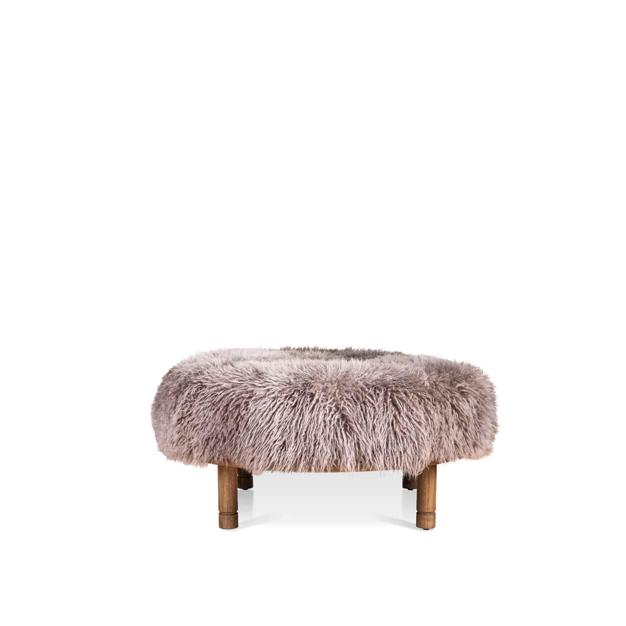 Grey Sheepskin Moreno ottoman by Lawson-Fenning. The Moreno Ottoman features a round solid wood base with four cylindrical legs and an upholstered top. Available in American walnut or white oak. 

The Lawson-Fenning Collection is designed and