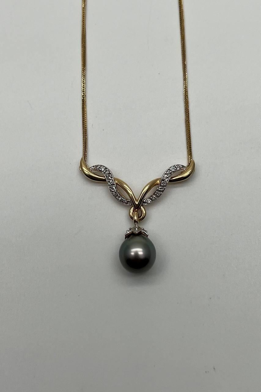 Una splendida collana di perle e diamanti.
Presenta una singola perla nera lucente, sospesa con eleganza. Il design è impreziosito da diamanti scintillanti incastonati in un grazioso motivo a onda.
La collana è realizzata in oro giallo lucido e