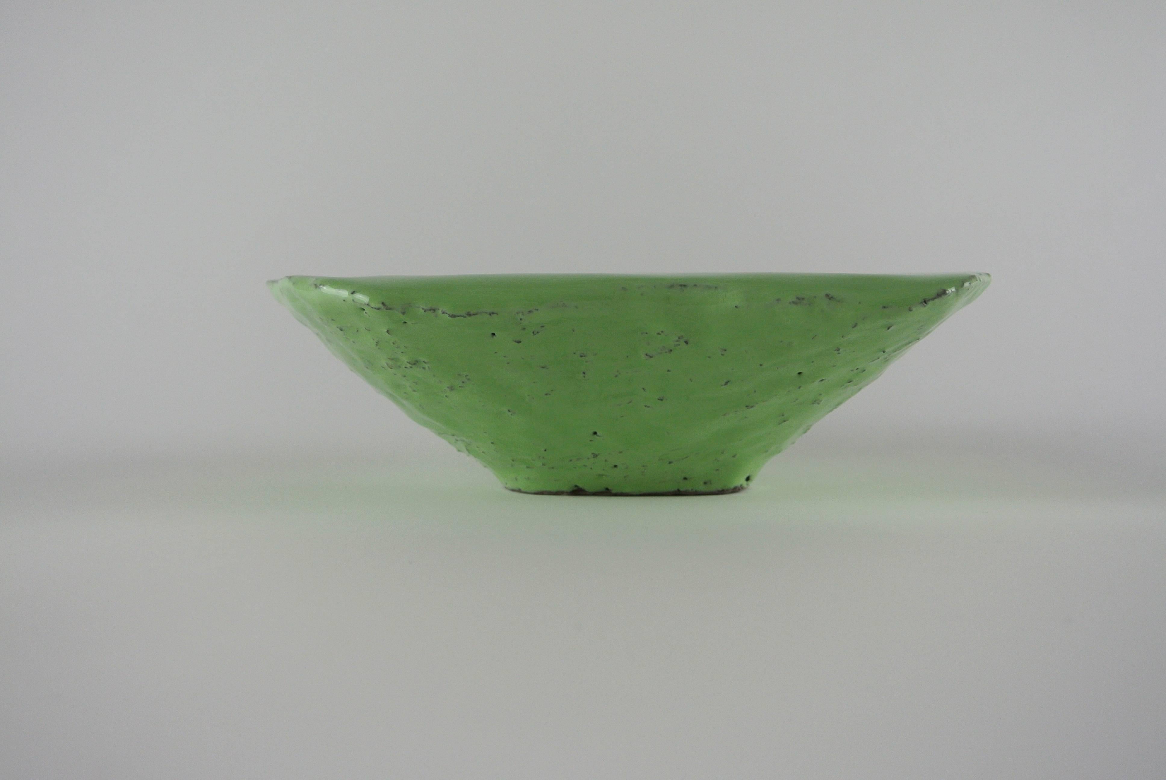 Asymmetric grey stoneware platform with visible black fire sand on parts of the surface. Lichen green glossy glaze. Crater like dent on one side.
Decorative.