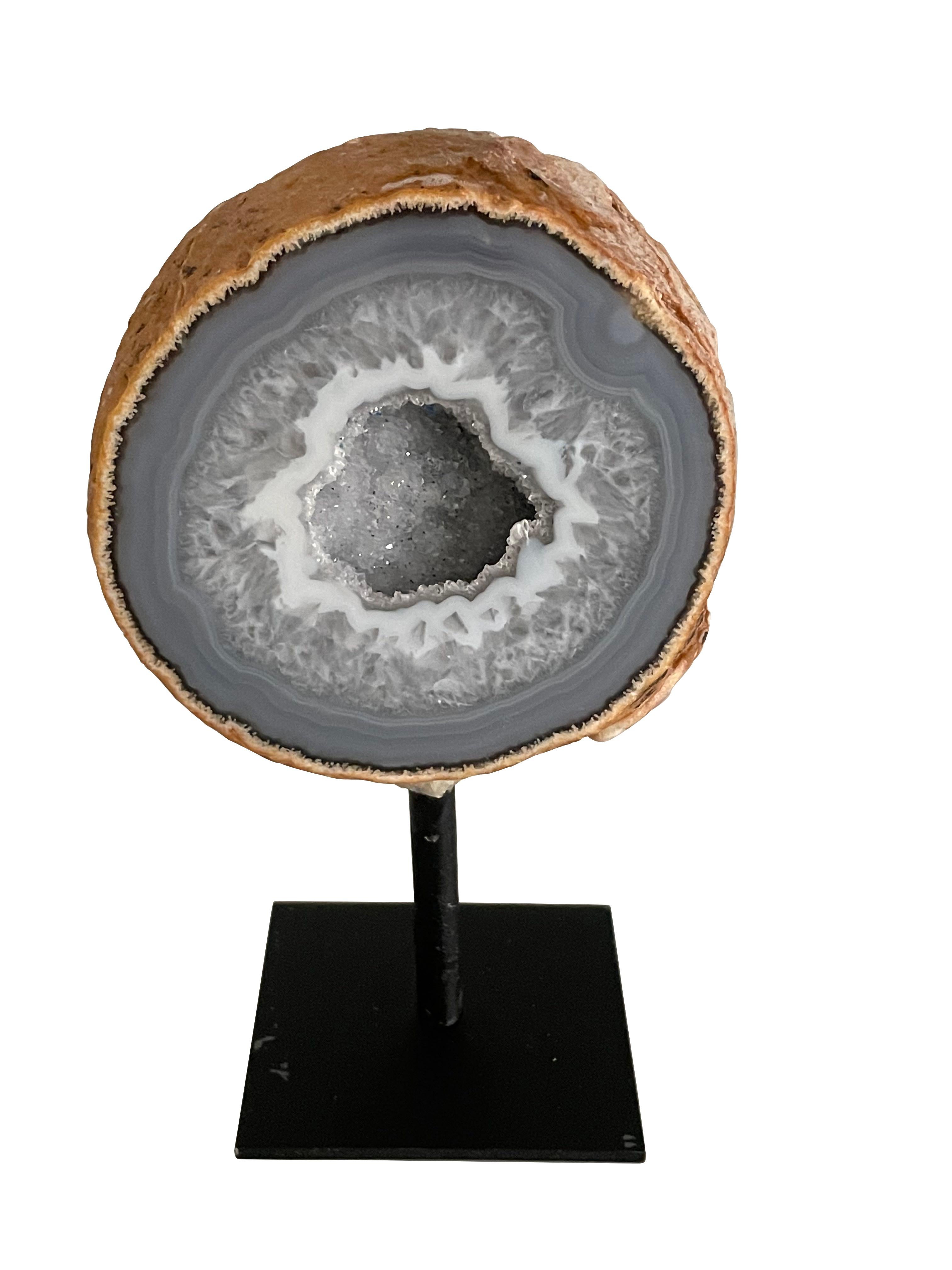 Grey Brazilian thick slice of agate mounted on a steel stand.
Agate is a banded form of finely-grained, microcrystalline Quartz. 
The lovely color patterns and banding make this translucent gemstone very unique. 
Agates can have many distinctive
