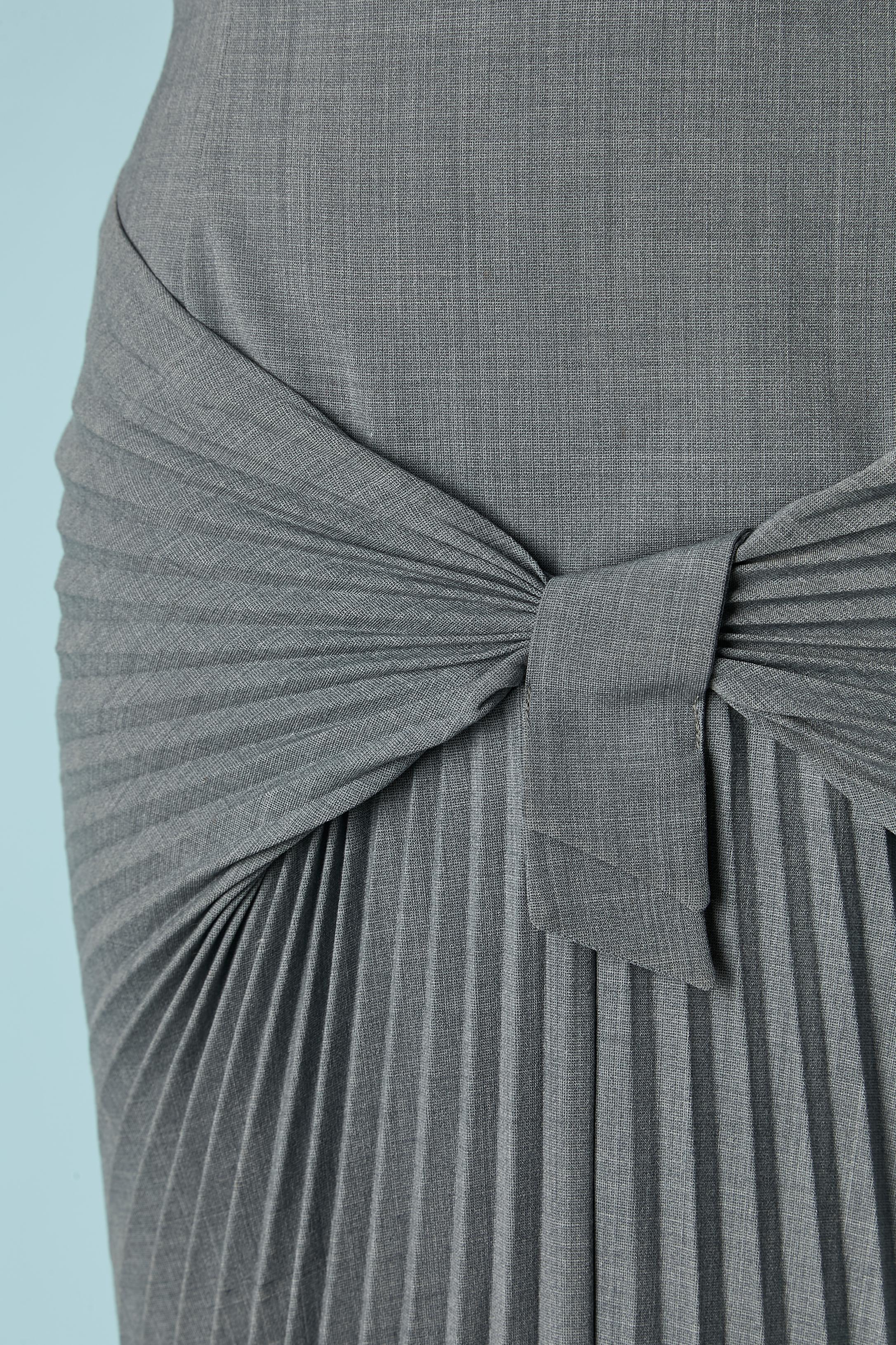 Jupe en laine fine grise avec plis soleil sur le devant. 
Composition du tissu extérieur : 52% laine, 40% polyester, 5% polyamide, 3% élasthanne. Composition de la doublure : probablement de la rayonne avec un bord inférieur en dentelle jaune.