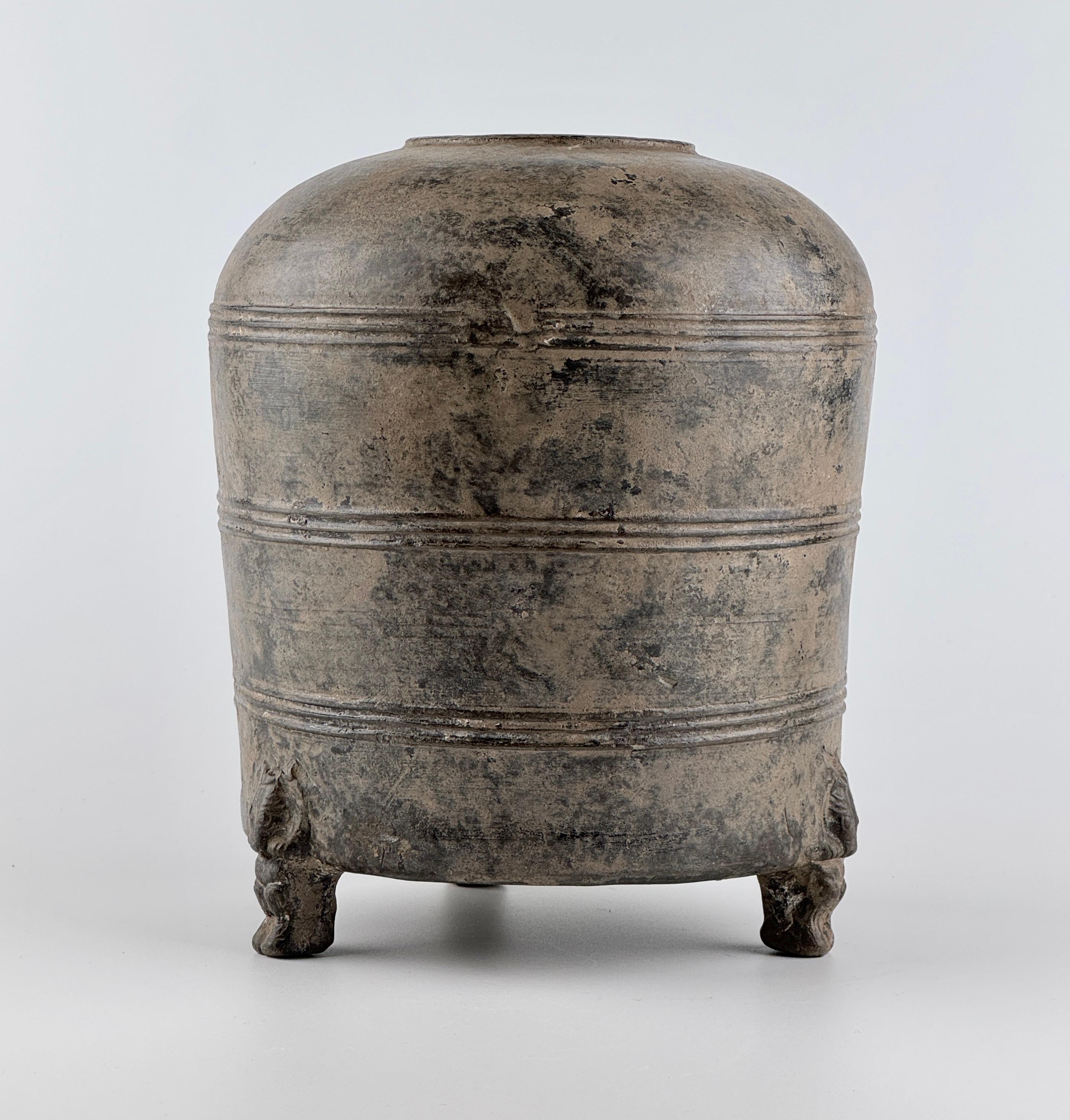 The vessel consists of a rounded cylindrical body, a gently curved upper section, and a small circular opening, suggesting that it was used for storing grain or valuable goods.

Three parallel decorative bands encircle the body, creating a simple