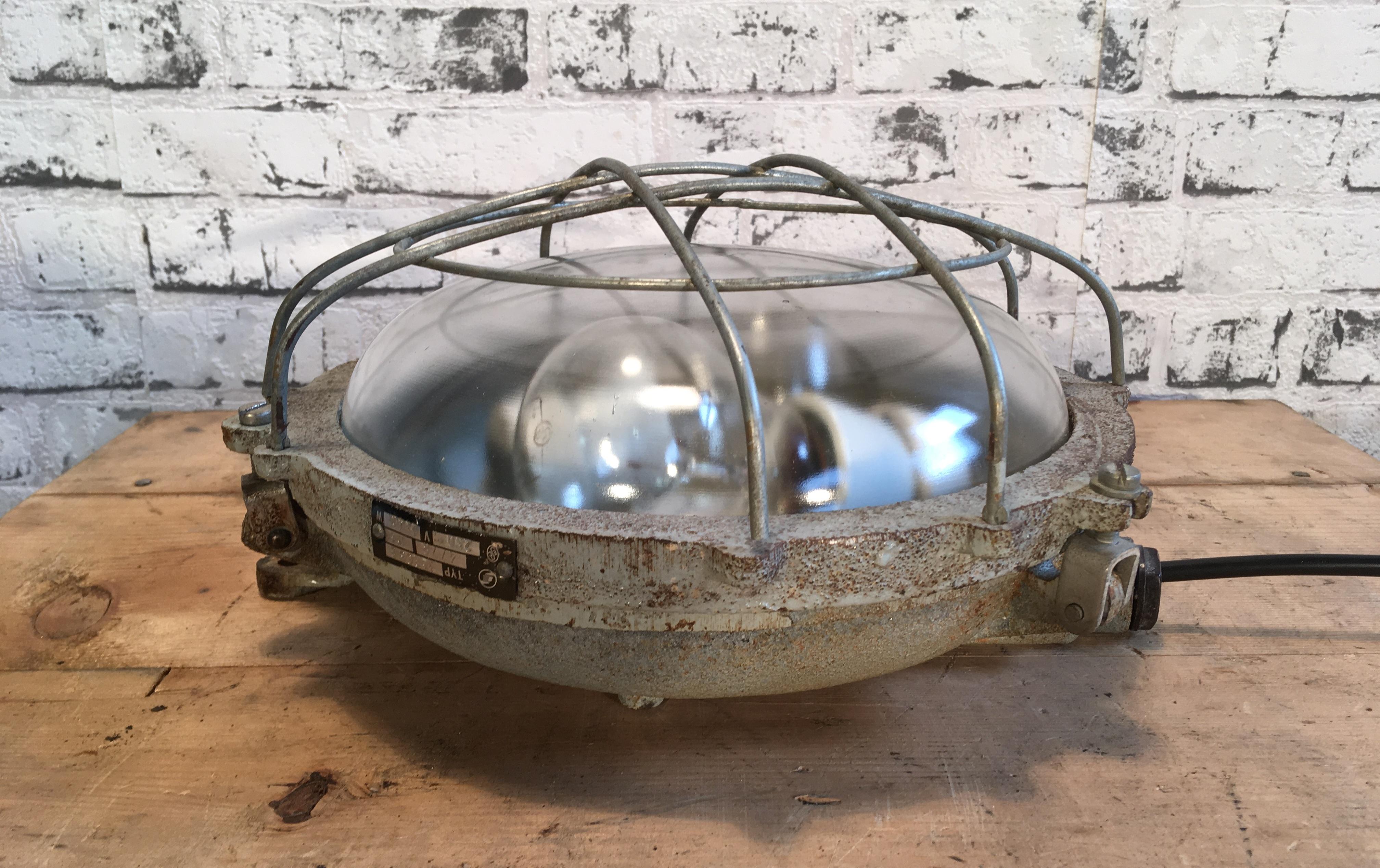 This cast iron wall lamp was made by Elektrosvit in former Czechoslovakia during the 1970s. It has two new porcelain E27 sockets, clear curved glass cover and steel grid. It can also be used as a ceiling lamp. Weight of the lamp is 6 kg.