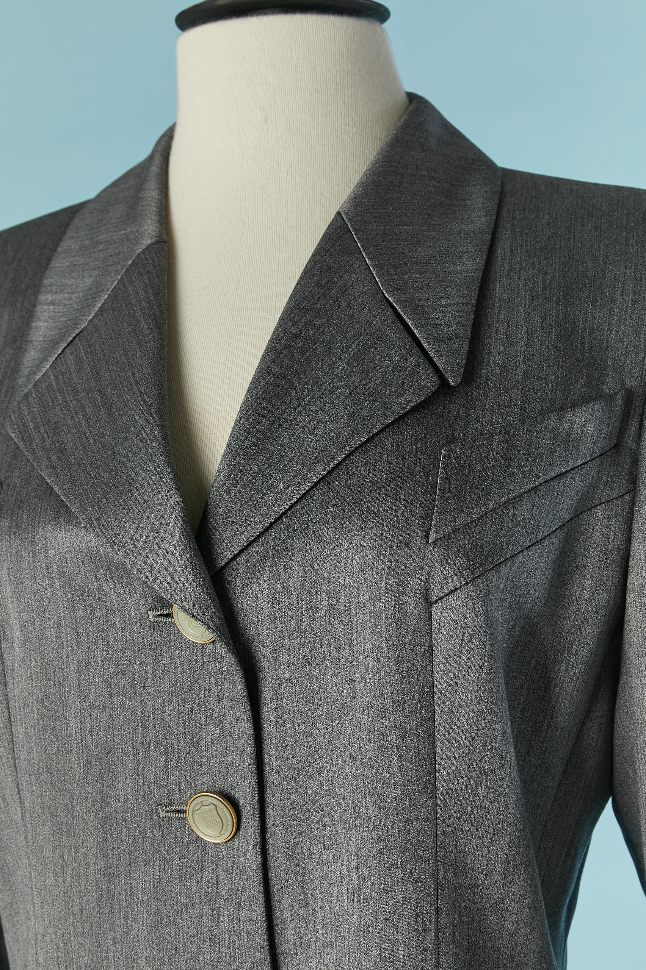 Grey wool and rayon skirt-suit . Main fabric composition: 56% wool, 39% rayon, 5% nylon. Lining composition: 100% rayon. 
Button and buttonhole closure on the middle front + on cuffs. Shoulder-pad. Pockets on both side. 
SIZE 36 on tag but the