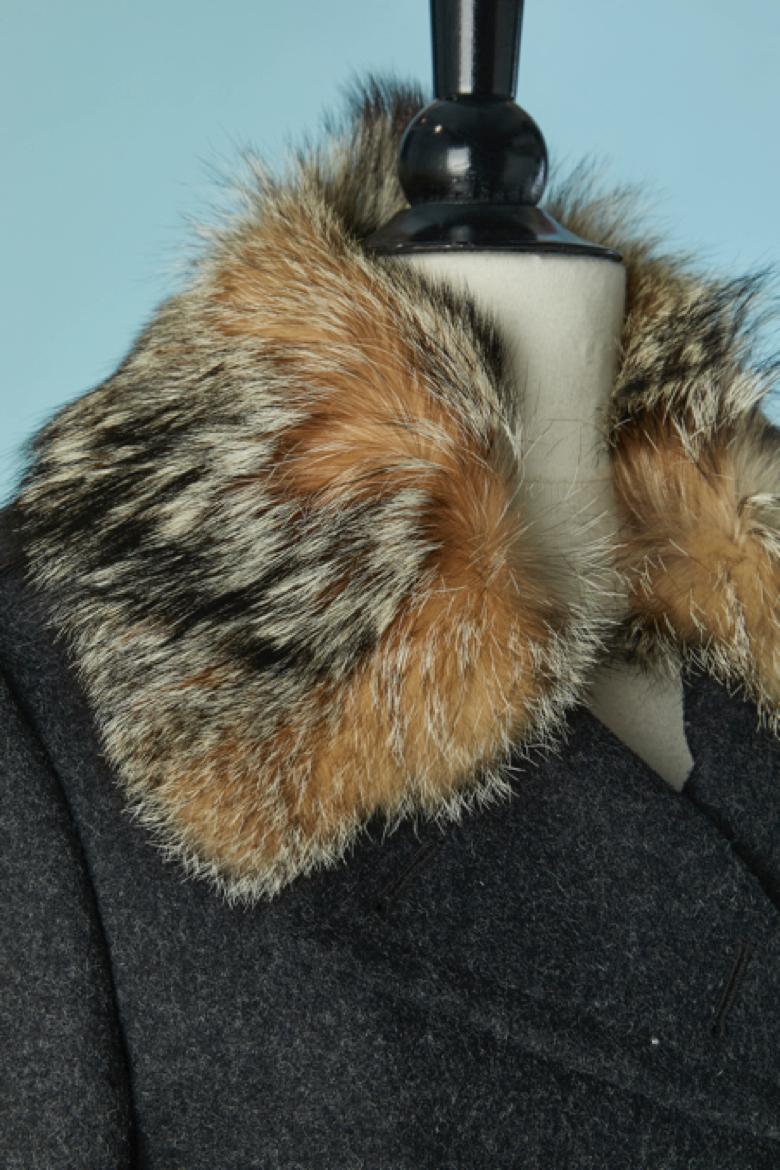 Cappotto doppiopetto imbottito in lana grigia con collo in pelliccia. Chiusura con bottone, bottone e zip nascosta sulla parte centrale del davanti. Composizione del tessuto principale: 80% lana, 20% poliestere. Composizione del pad e della fodera: