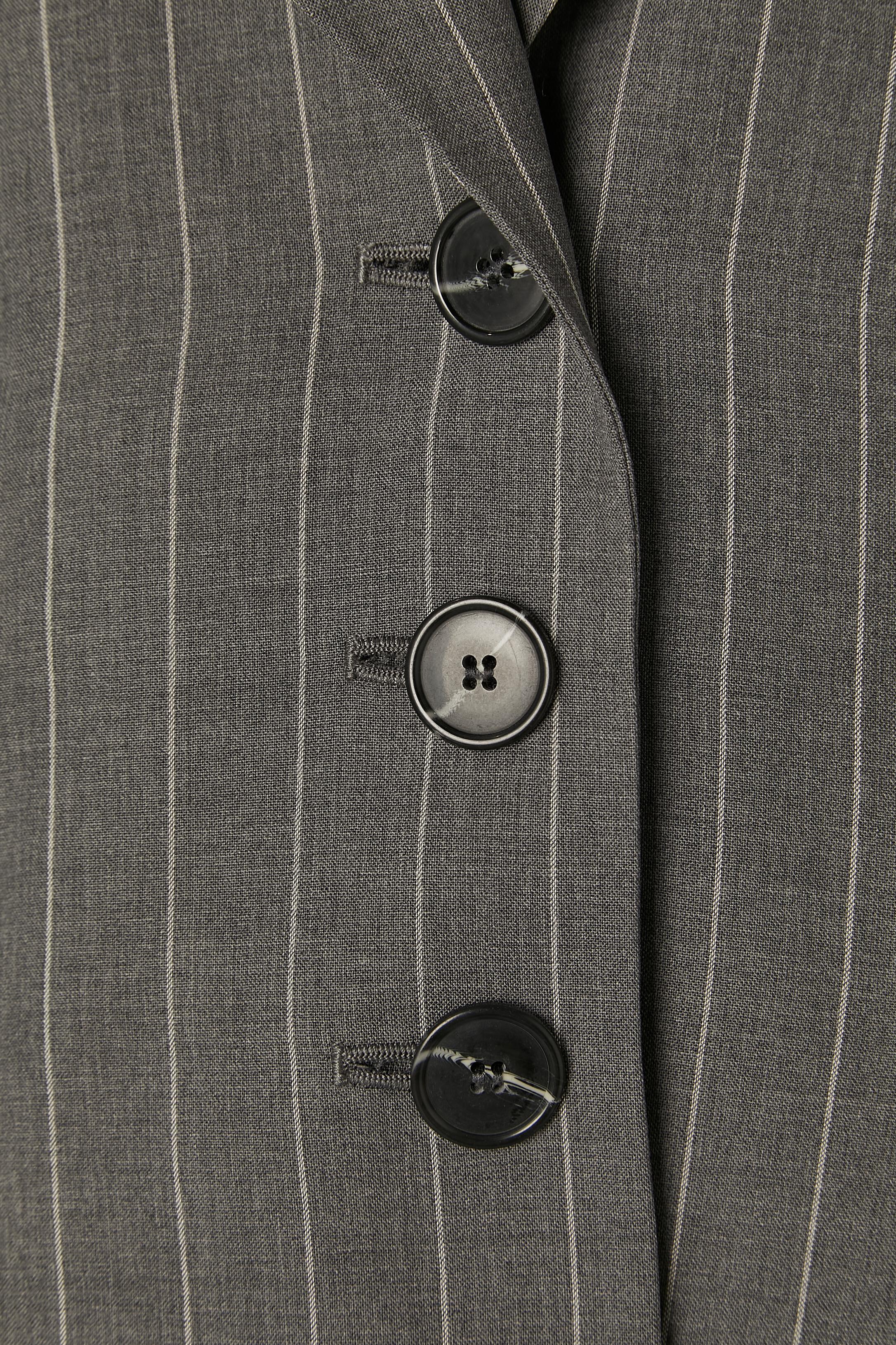Grey wool pin-striped coat and trouser ensemble . Main fabric composition: 99% wool, 1% polyester. 
Lining composition: 55% acetate, 45% rayon. 
Button and buttonhole closure on the middle front. Pocket on both side + one decorative pocket flap.