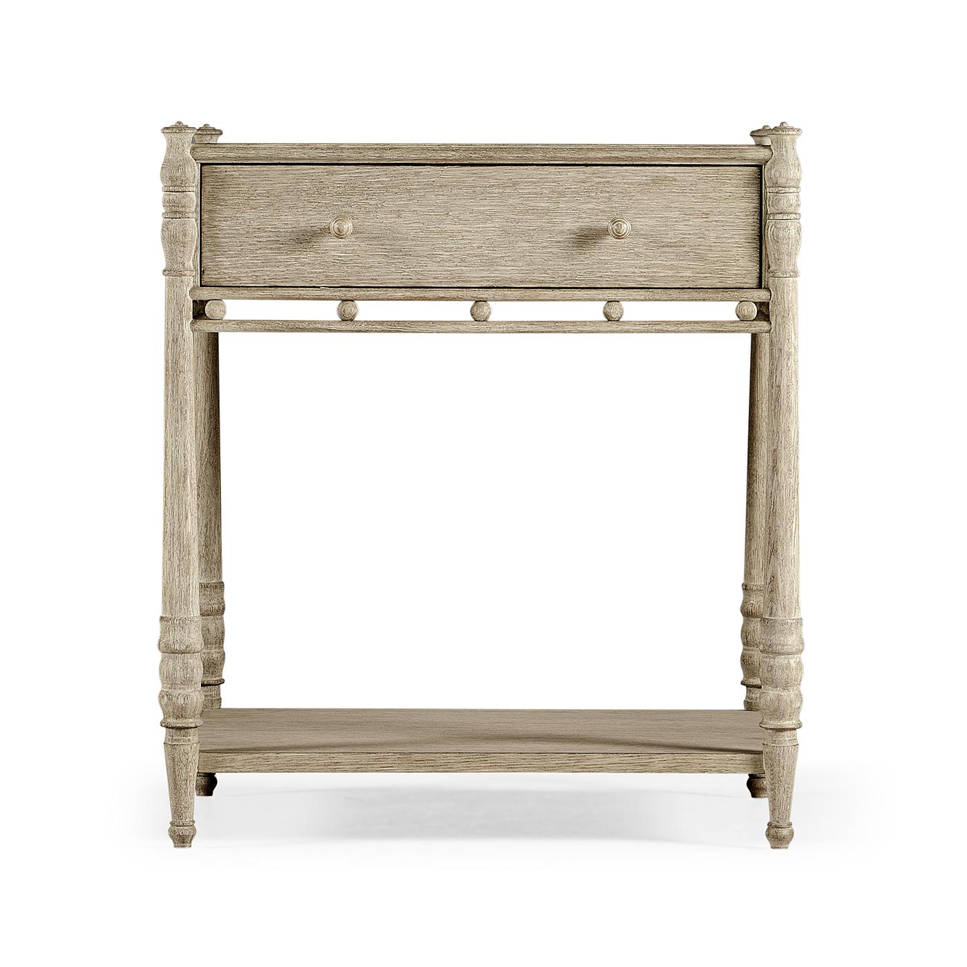 Crafted from premium oak and finished in a sophisticated washed grey oak, this piece seamlessly blends rustic charm with transitional style. Intricate wood carving details, turned legs with urn accents, and an open fretwork design below the drawer