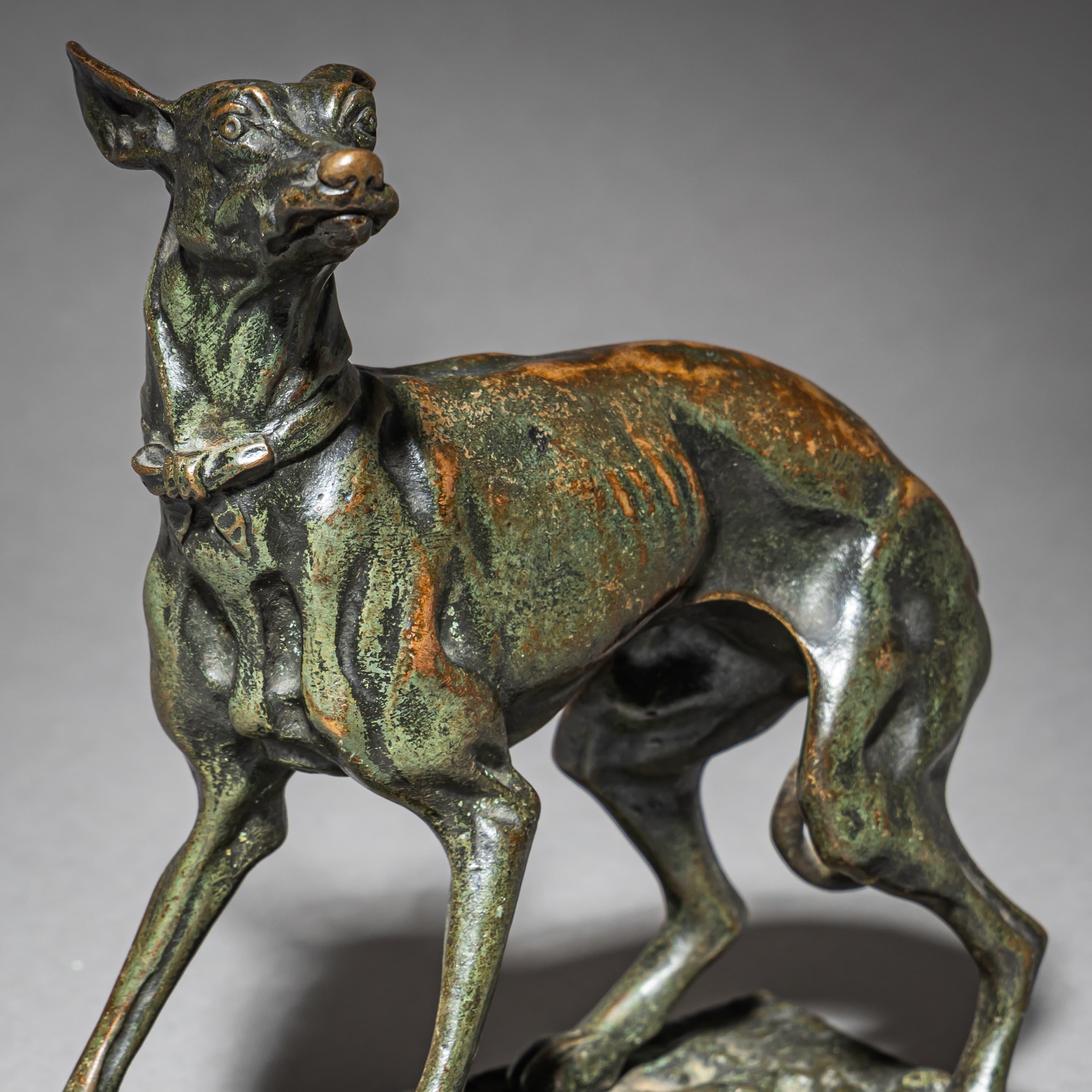 Piccola scultura in bronzo di un levriero con patina verde. Il cane è raffigurato in una posa calma e attenta, con dettagli anatomici finemente resi. Firmato Fratin sulla base. Un'opera caratteristica del famoso scultore di animali francese del XIX