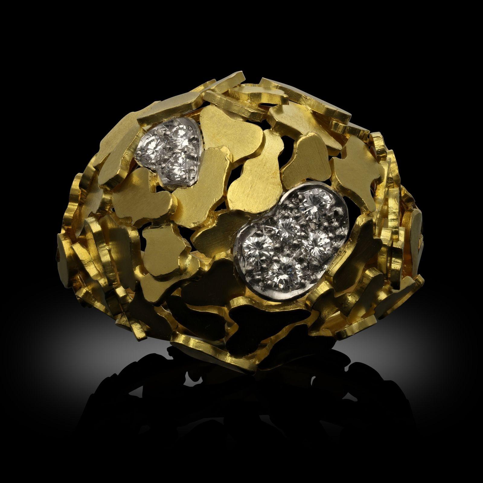 A vintage 18ct yellow gold and diamond ring by Andrew Grima, 1967. The ring is made up of 18ct yellow gold asymmetric flat 'pebbles' which overlap to create the bombe shape, the ring is accented with two diamond panels with grain set round brilliant