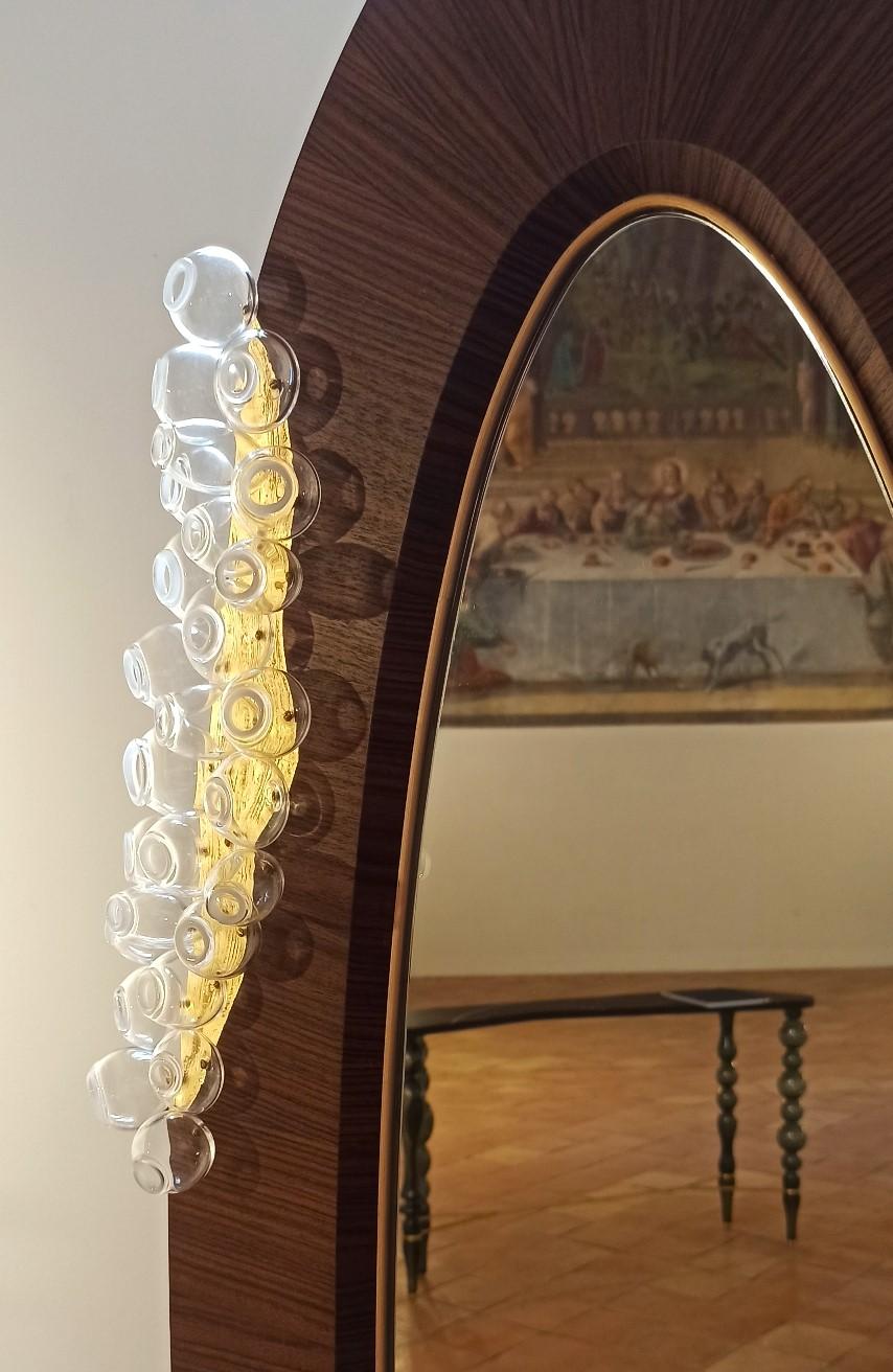 Der Spiegel von Grimilde ist ein raffinierter, handgefertigter Bodenspiegel.
Giordano Viganò und Simone Crestani haben Holzbearbeitung und Glasbläserei kombiniert, um diesen malerischen und dekorativen Spiegel zu realisieren, der sowohl für das