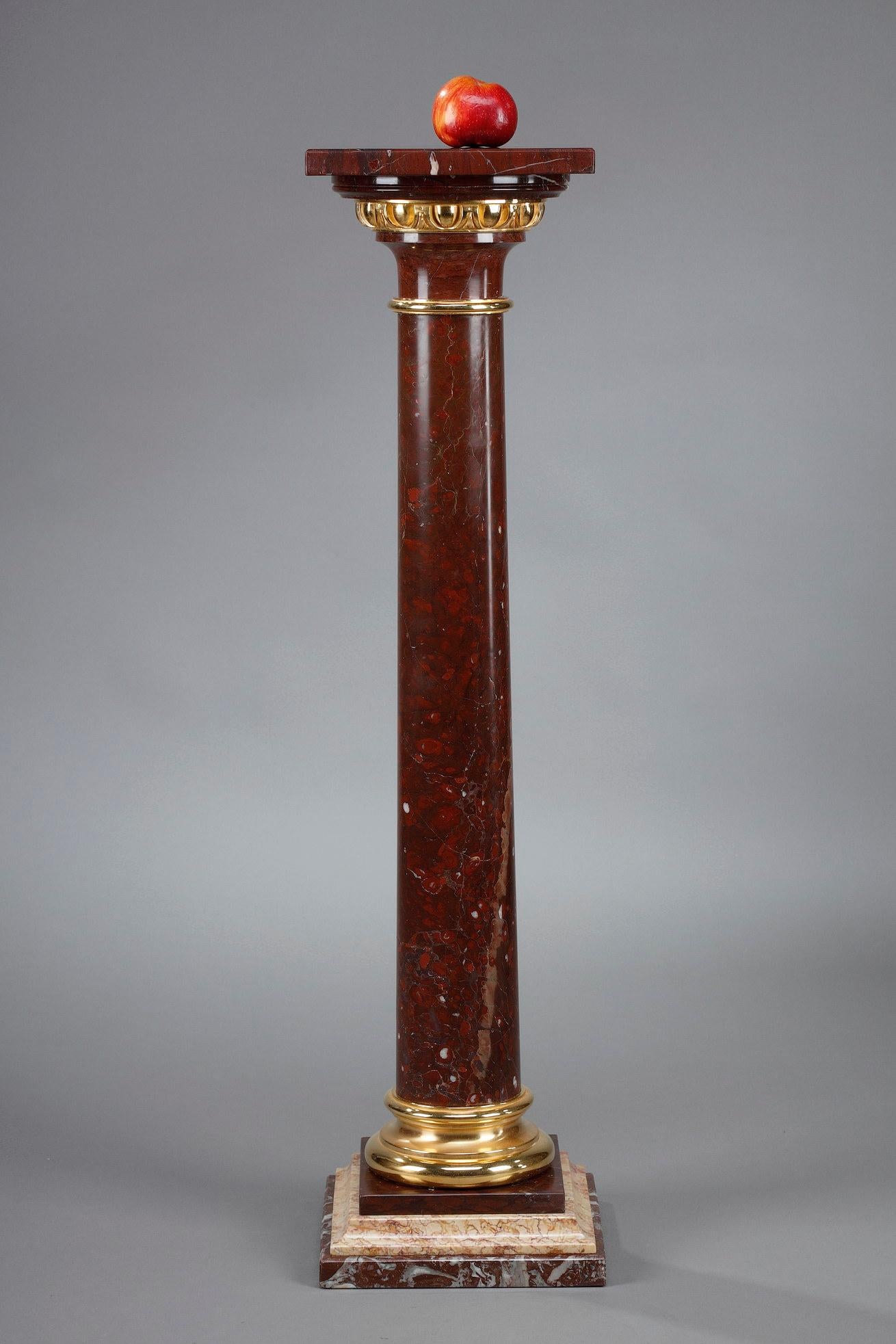 A late 19th century column in griotte red marble with a circular shaft topped by an Ionic capital composed of a bronze moulding decorated with oves hosting the square top. The attic base is composed of three quadrangular tiers of different red, pink
