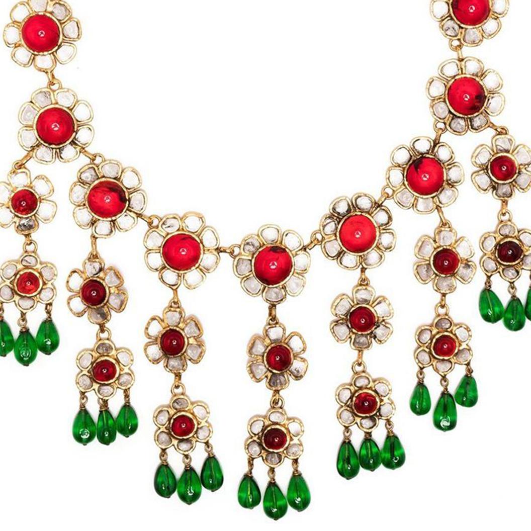 Designed by Gripoix in the style of Chanel, this unique vintage piece displays an array of red and white glass flowers set in gold-toned metal, finished with green glass beads. Designed to uplift any outfit, this necklace is sure to make a