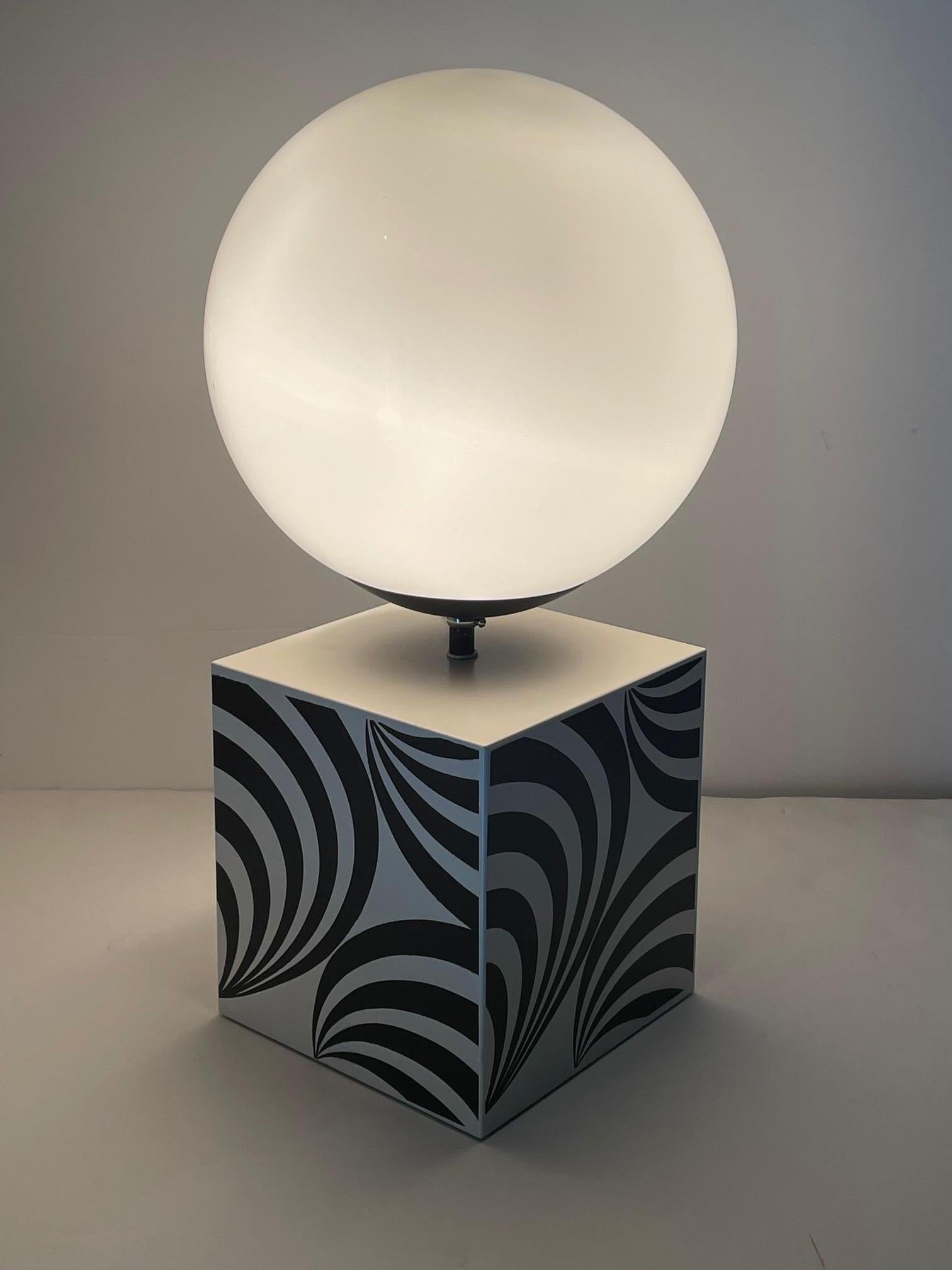 Super funky table lamp, or is it art? The base is a black and white op art decorated cube with glowing round milk glass globe mounted on top. Austin Powers would love this groovy treasure.
Base 7.25 x 7.25
Globe is 9