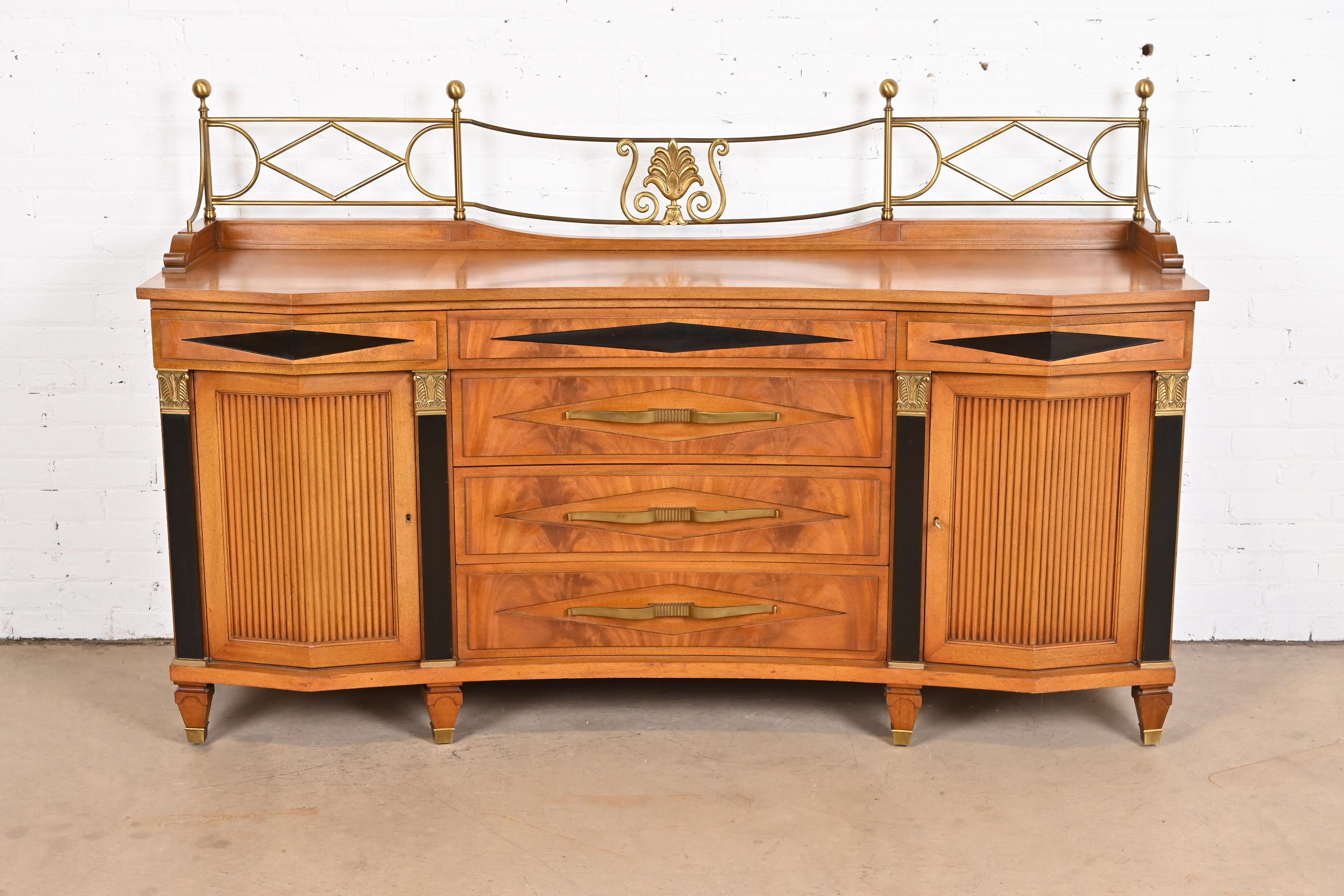 A gorgeous Hollywood Regency or Neoclassical sideboard, credenza, or bar cabinet.

By Grosfeld House.

USA, mid-20th century.

Mahogany, with ebonized details, and original brass hardware and gallery. Cabinets lock, and key is