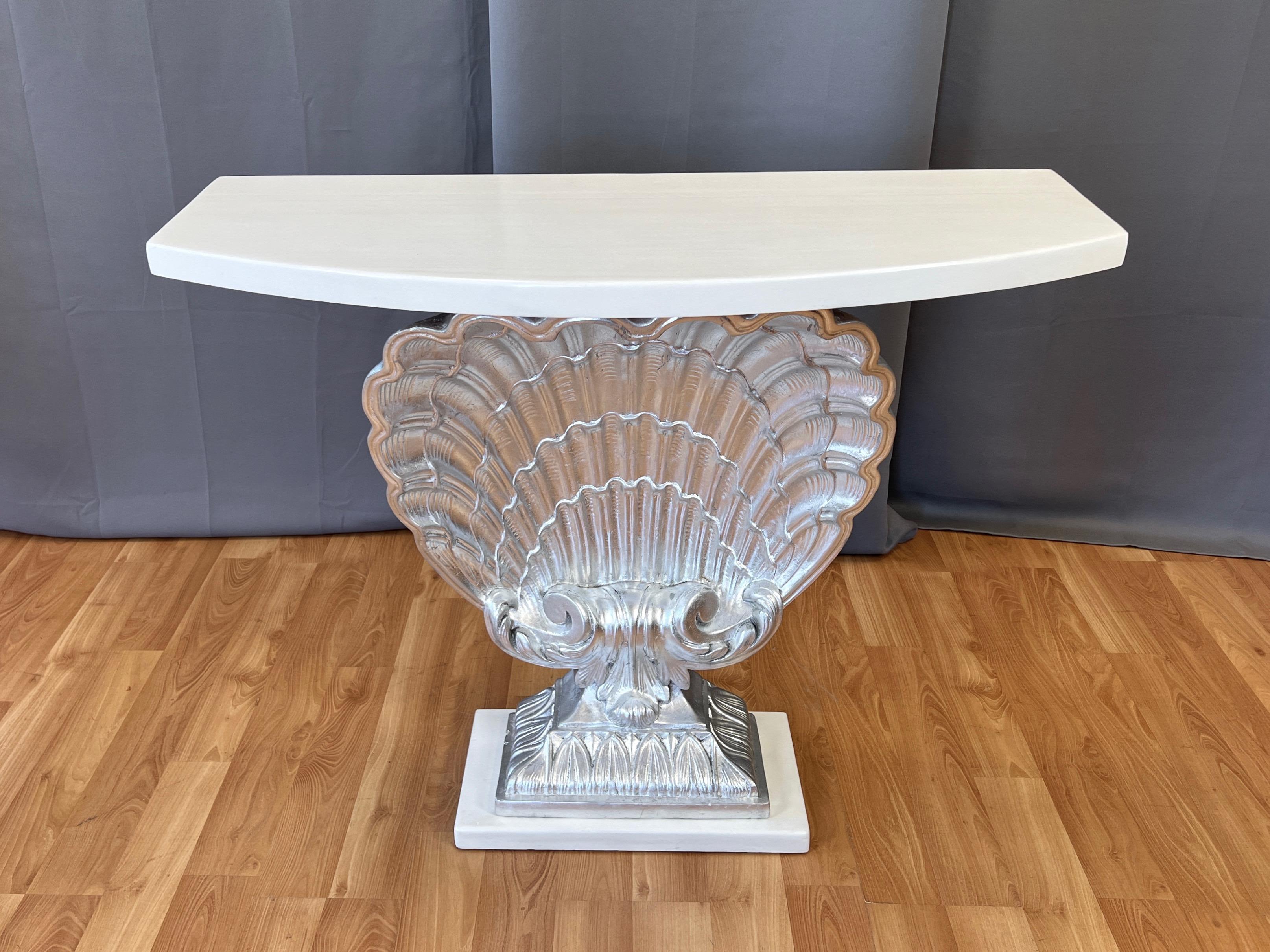 A stunning 1940s Hollywood Regency silver-leafed shell console table with white lacquered top and base by Grosfeld House.

Exceptionally well-sculpted and exquisitely detailed monumental cast plaster scallop shell on integrated ornamental pedestal.