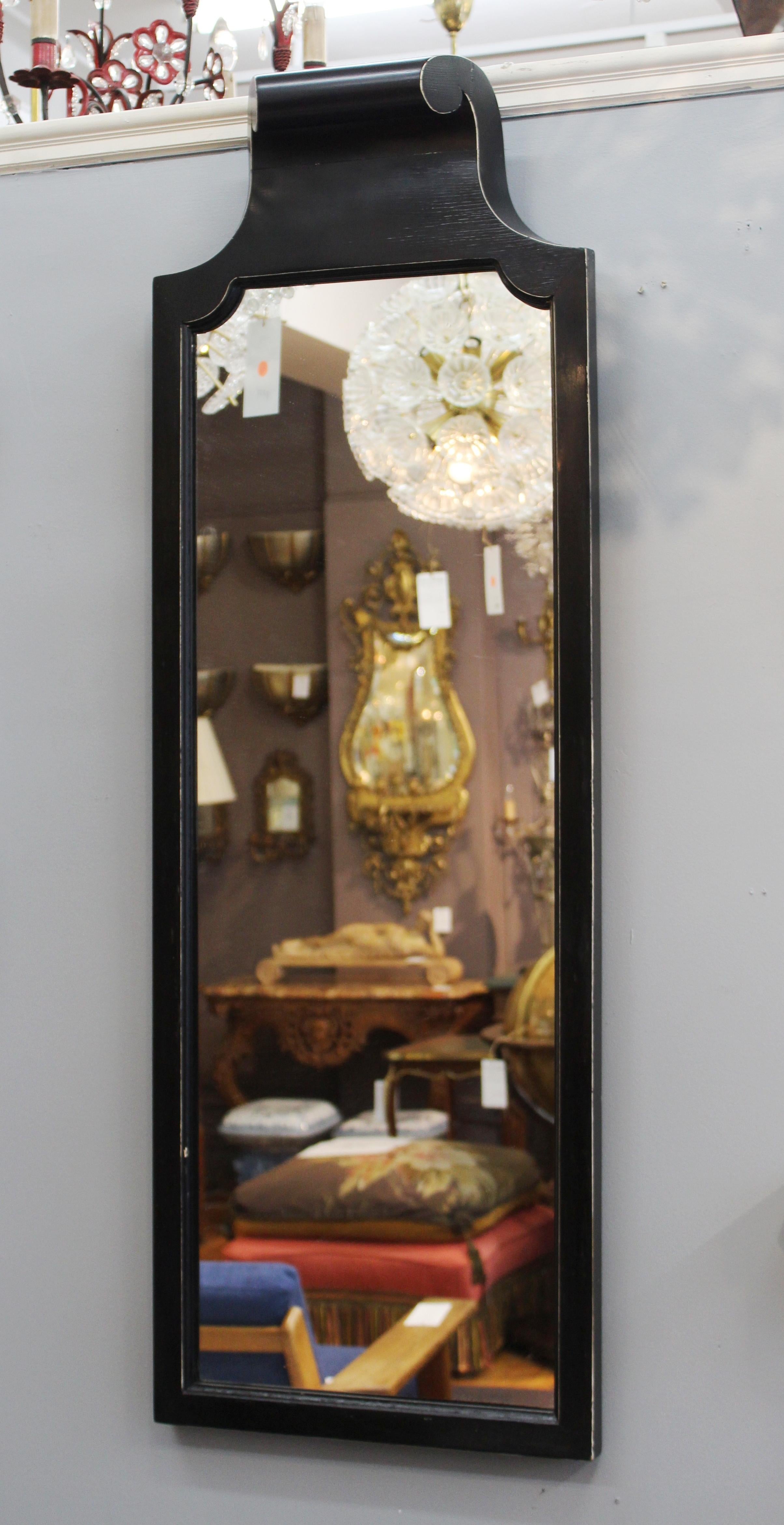 Grosfeld House classic style console with matching mirror in ebonized wood. The table mounts to the wall and stands on a scroll column. The mirror's crown mimics the scroll motif of the table. Some wear appropriate to age and use including chips and
