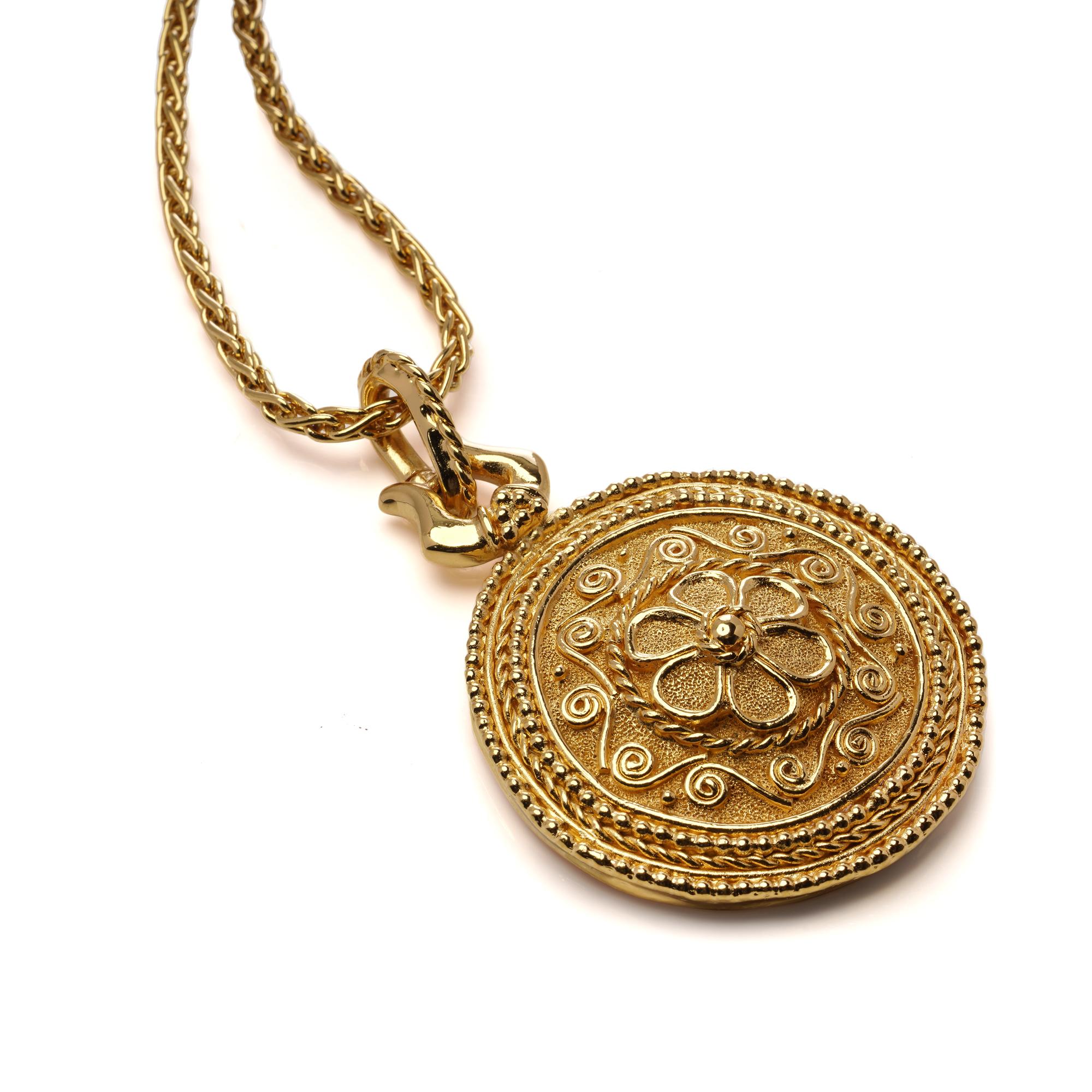 Vintage-Halskette mit Anhänger der Marke Grosse aus den 1980er Jahren. Dieses auffällige Stück besteht aus einem großen, runden Anhänger mit aufwändigen Golddetails und einem erhabenen Blumenmotiv, der an einer langen Seilkette hängt. Der Anhänger