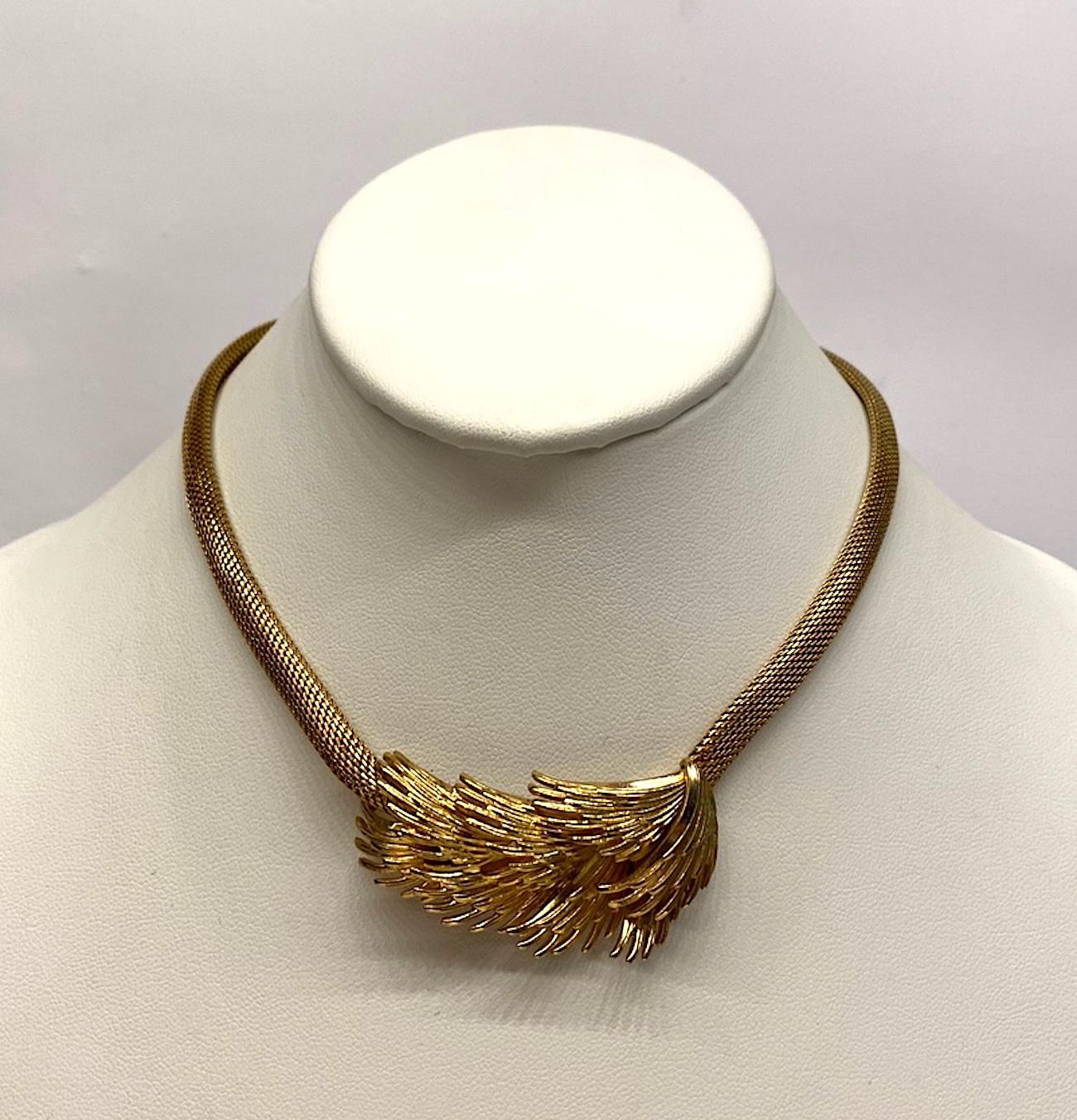 A lovely Grosse Germany necklace produced in 1966. It consists of a finely woven mesh strand with three dimensional abstract center piece of overlapping wings. The mesh strands are .25 of an inch wide. The center piece measures 2 inches wide and 1