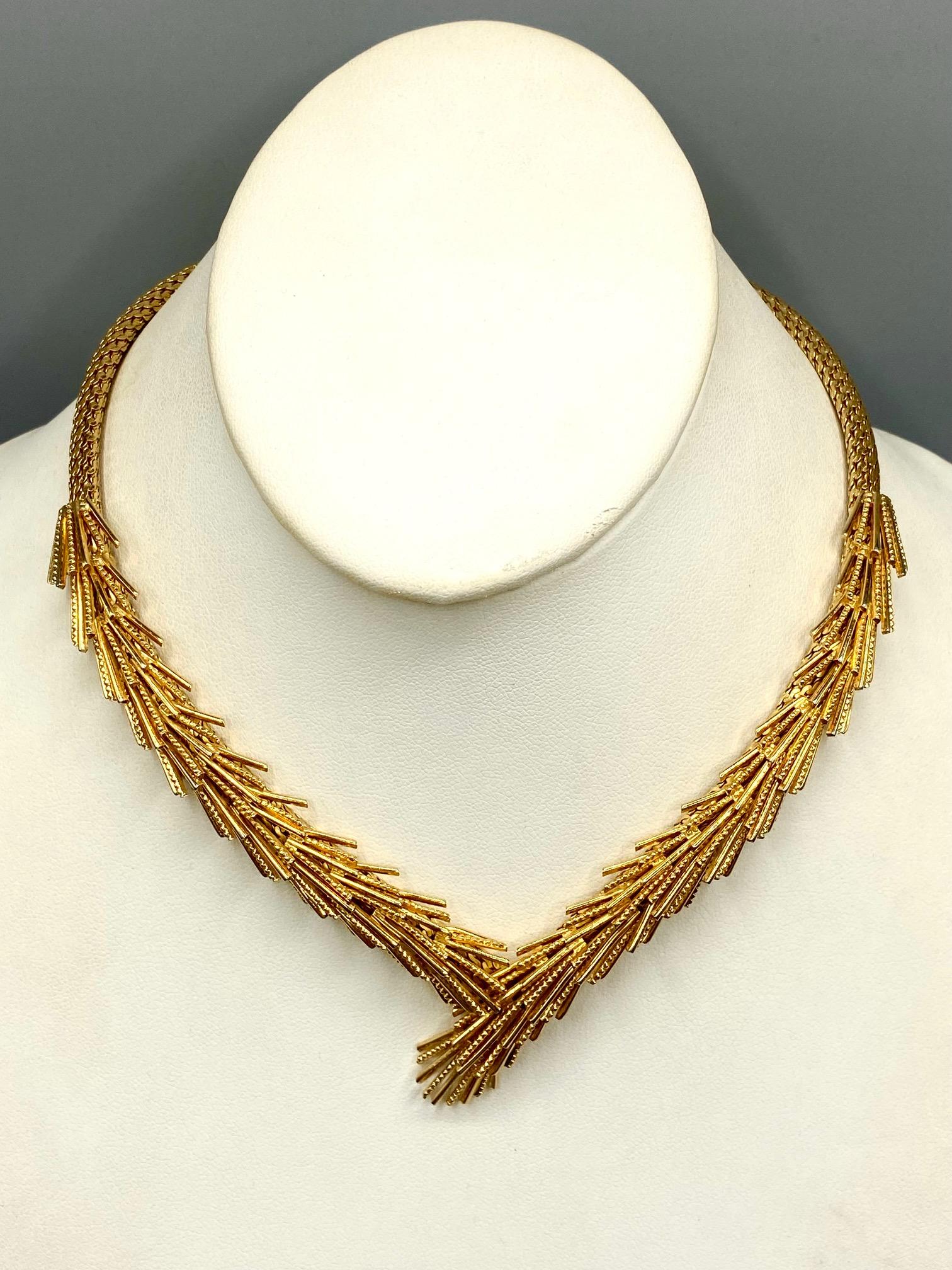 Abstract link cross over necklace by well known German fashion jewelry company Henkel & Grosse. The front half of  the gold tone necklace has an overlapping fringe or brush design in alternating smooth and textured bars. The back of half is a wide