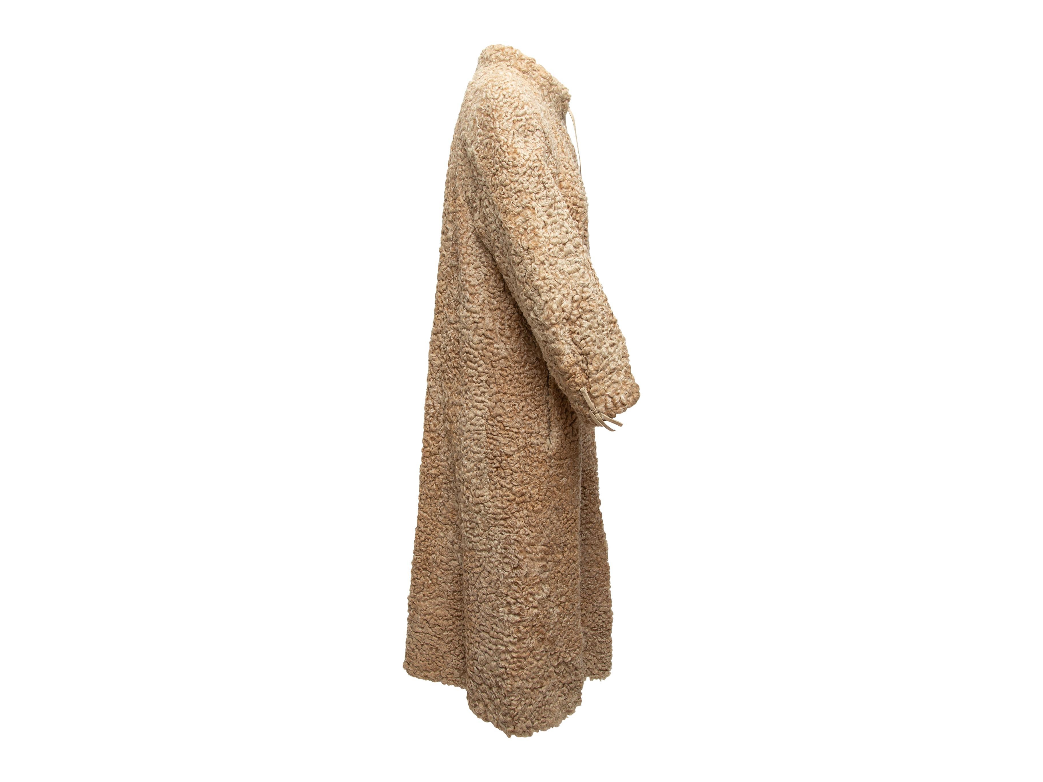 Product details: Vintage beige Persian lamb long coat by Grosvenor. Stand collar. Dual hip pockets. Tie closure at front neckline. 38